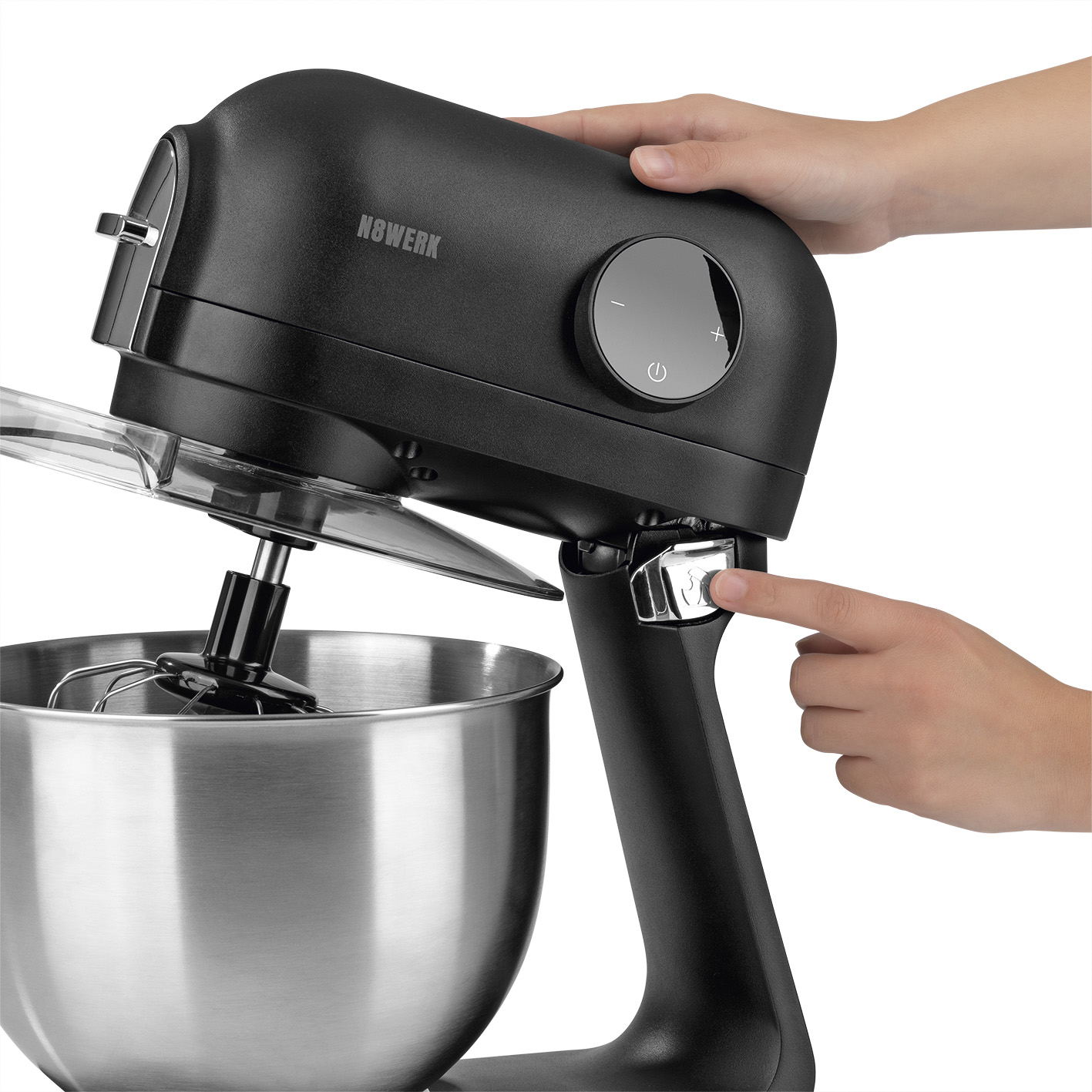 Ein schwarzer Küchenmixer mit einer Edelstahlschüssel, eine Hand drückt den Einschaltknopf.