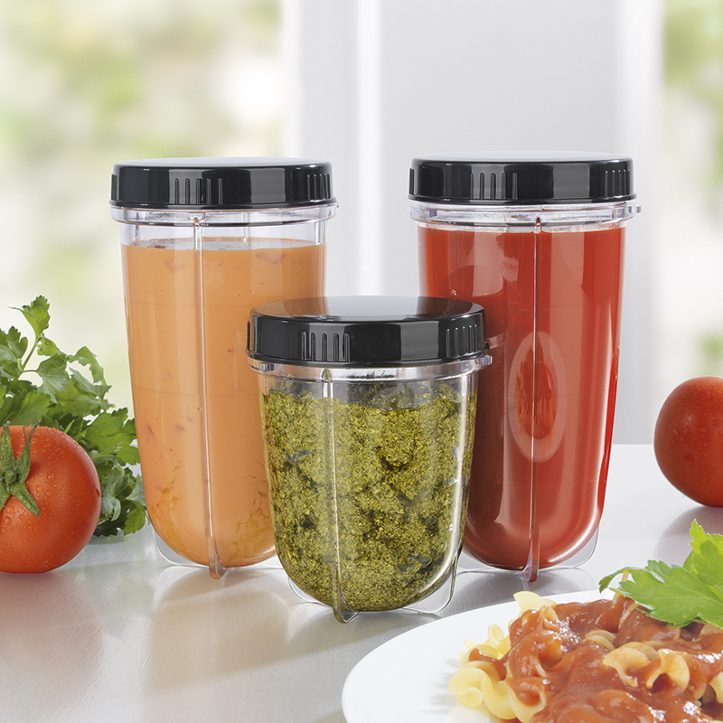 Tre contenitori per frullatore. Uno con pesto, uno con liquido rosso e uno con liquido arancione, tutti su un tavolo.