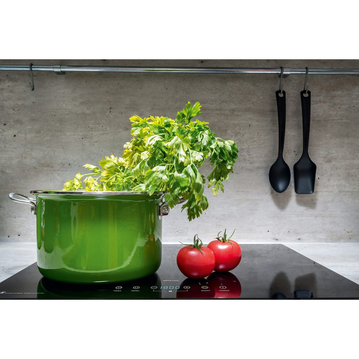 Casserole verte avec persil, tomates et surface de cuisson.