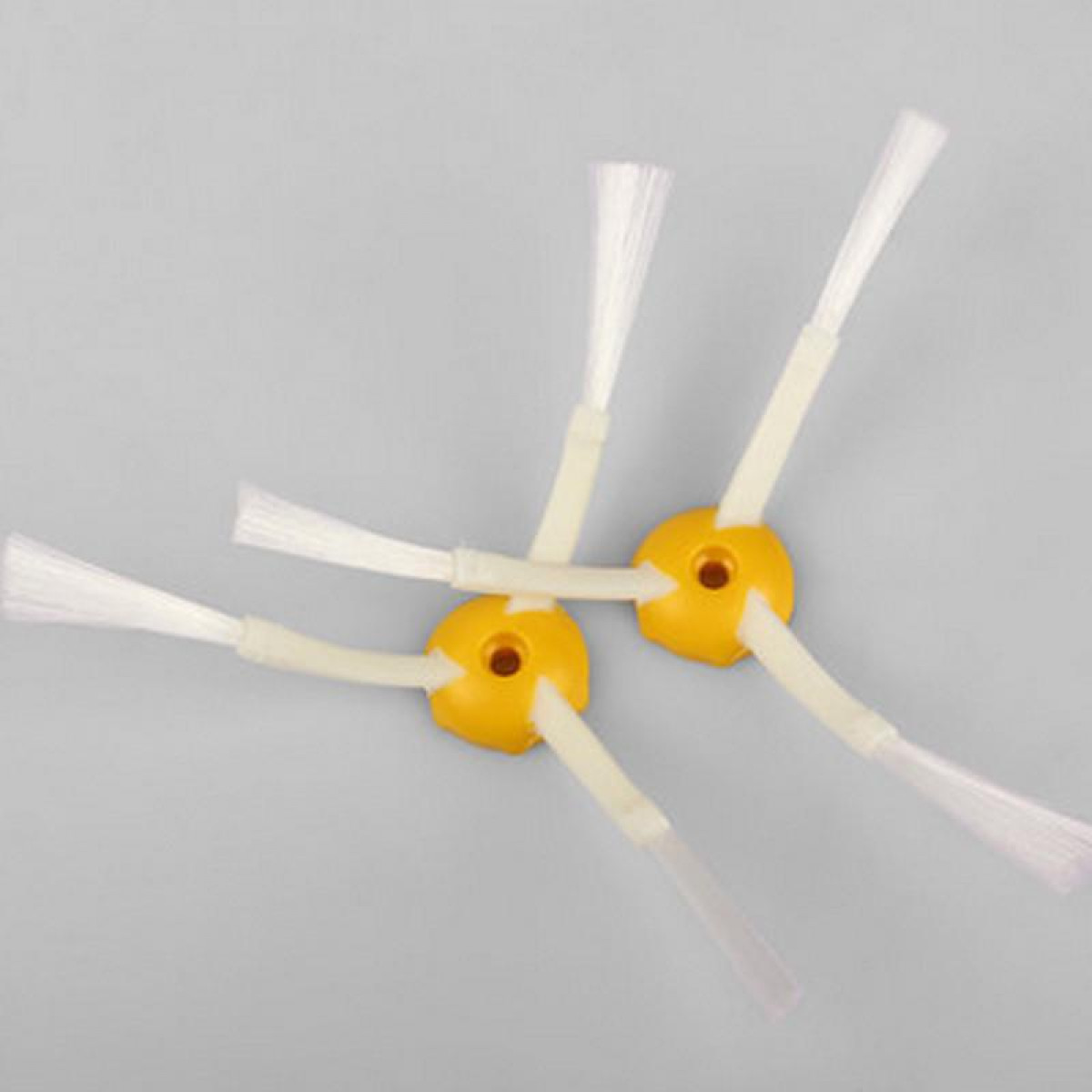 Żółte i białe szczotki do robota odkurzacza z białym włosiem na szarym tle.