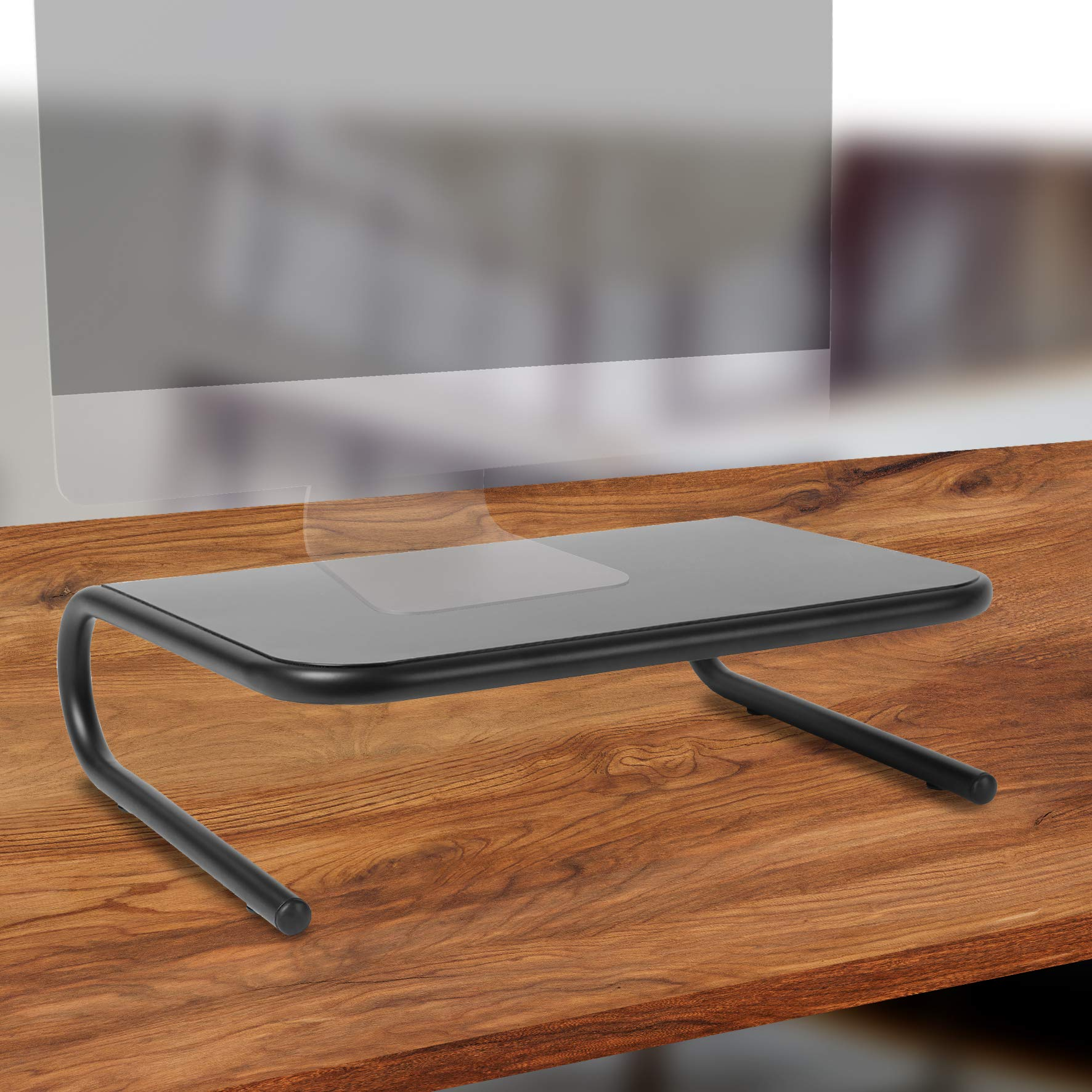 Ein schwarzer Monitorständer auf einem Holztisch. Der Ständer hat ein gebogenes Design und trägt den Monitor.