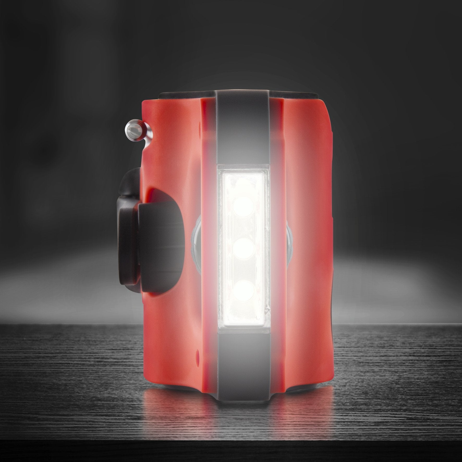 Rotes, schwarz-weißes Notlicht auf dunkler Oberfläche. Es hat ein helles weißes Licht und einen schwarzen Griff.