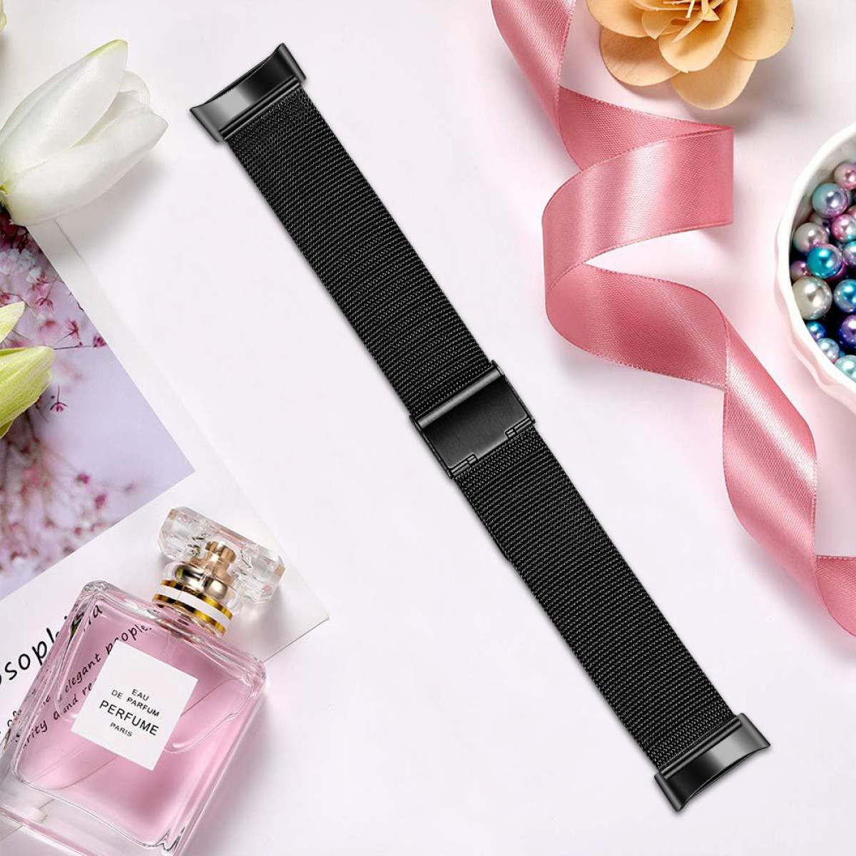 Schwarzes Uhrenarmband auf heller Oberfläche mit Parfüm.