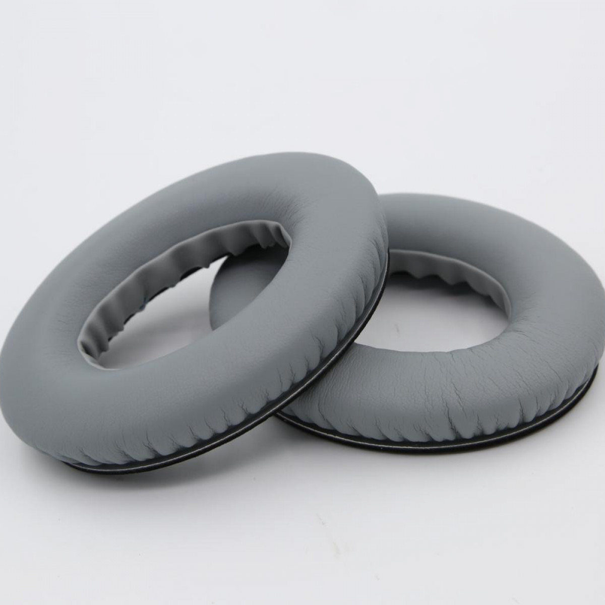 Dwie szare poduszki do słuchawek, obok siebie, na białym tle.