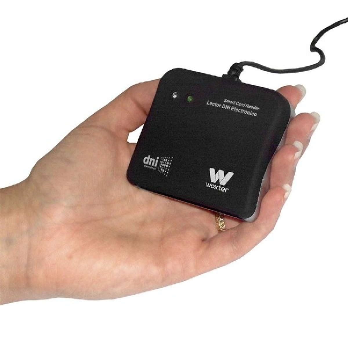 La mano sostiene un lector de tarjetas inteligentes negro. Tiene un cable y la marca 'Woxter'.