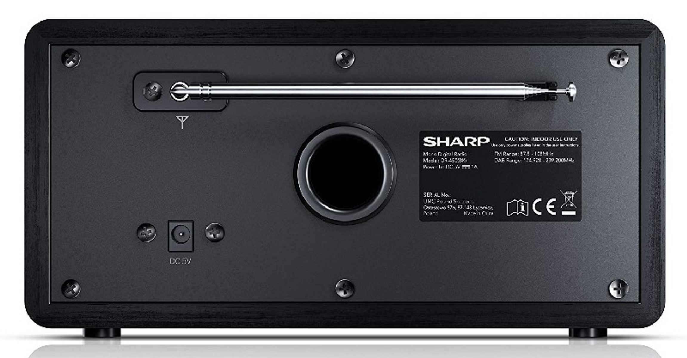 Parte trasera de radio Sharp negra con antena, puertos y etiquetas. El fondo es oscuro con textura de madera.