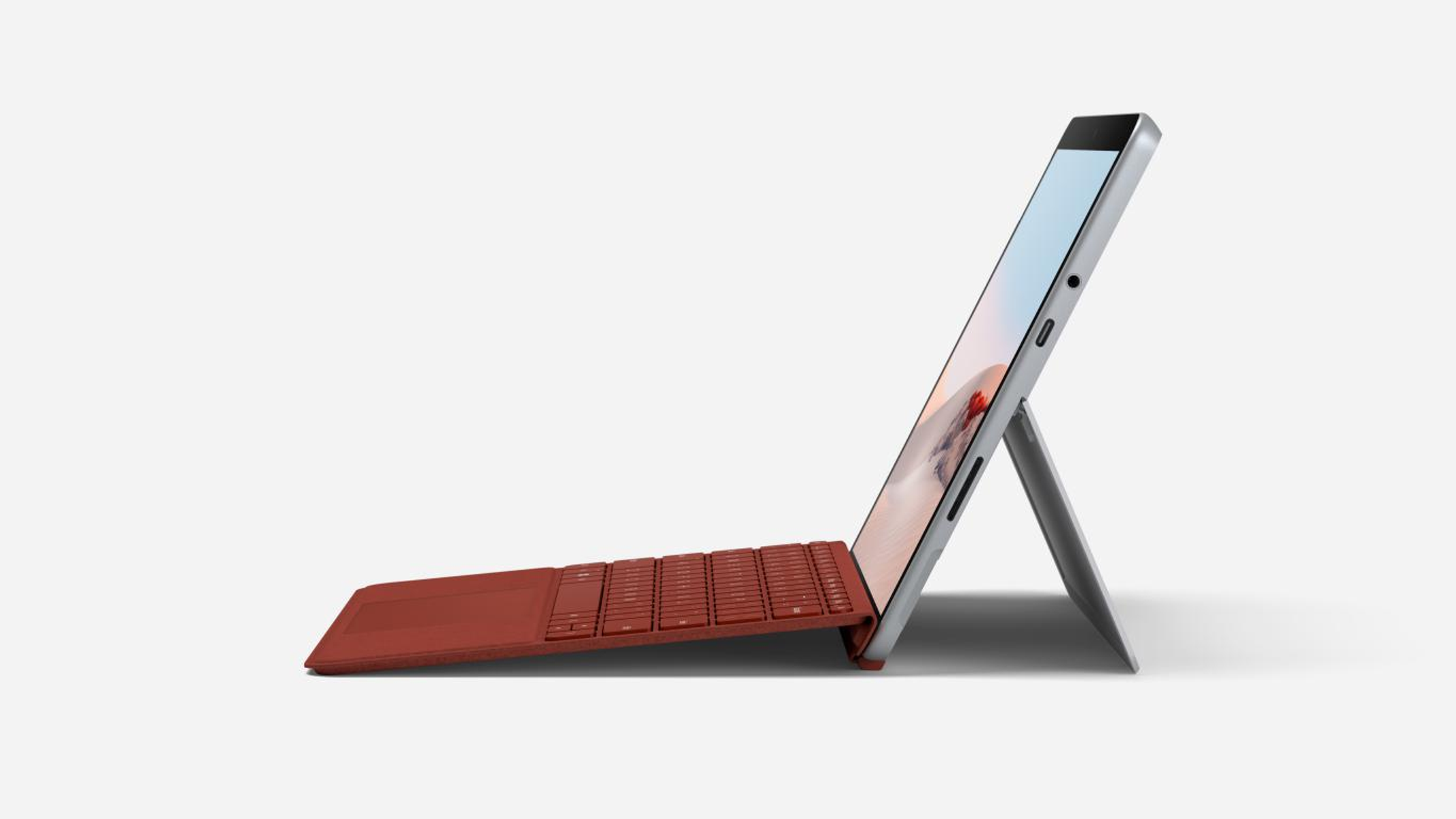 Teclado rojo y pantalla abierta. Portátil plateado sobre fondo blanco. La pantalla está en ángulo.