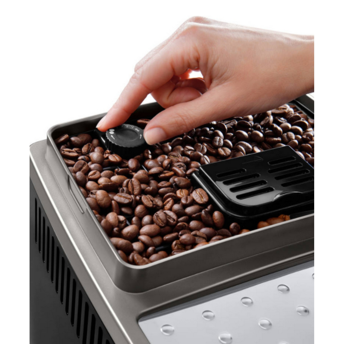 Una mano ajustando la configuración del recipiente de granos de una cafetera lleno de granos de café.