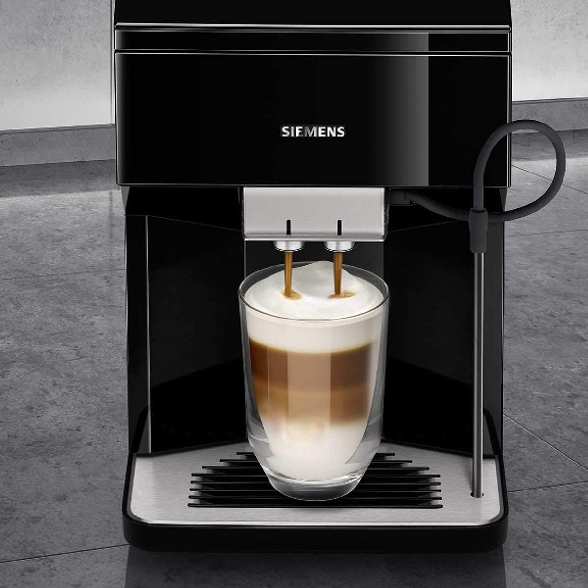 A black Siemens coffee maker with a glass of latte being made.