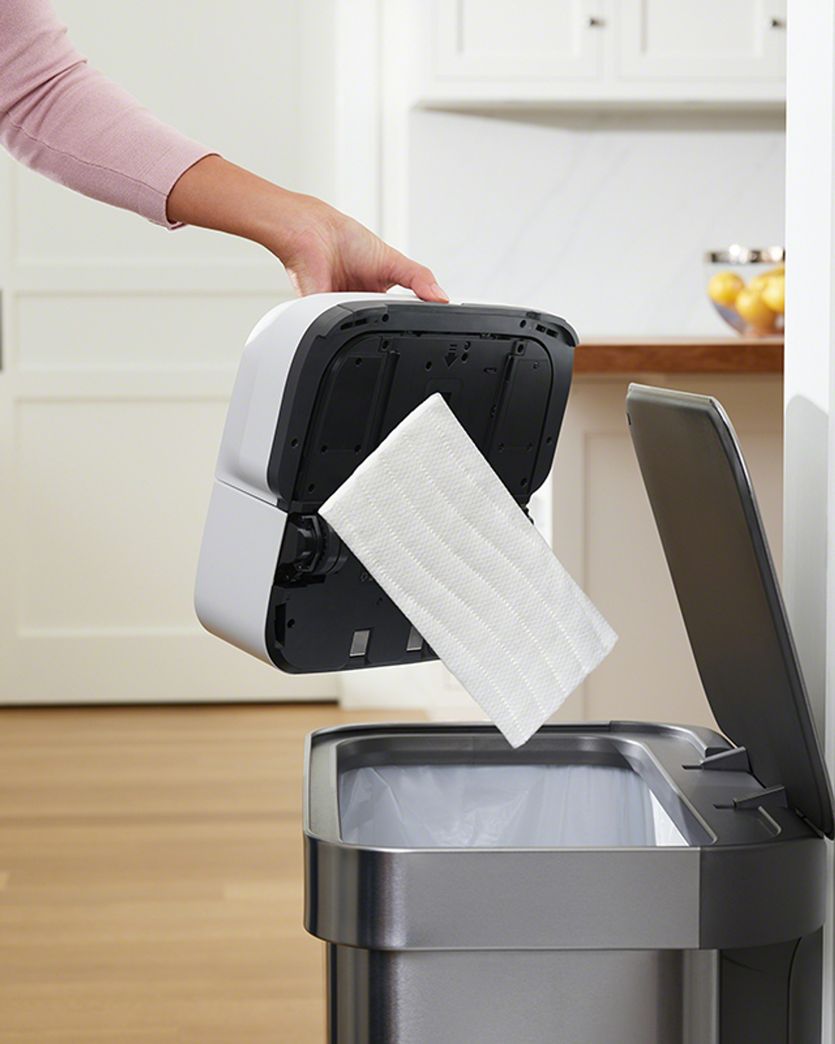 Mano che rimuove una testa di mop bianca da un cestino intelligente. Ambiente cucina, bianco e argento.