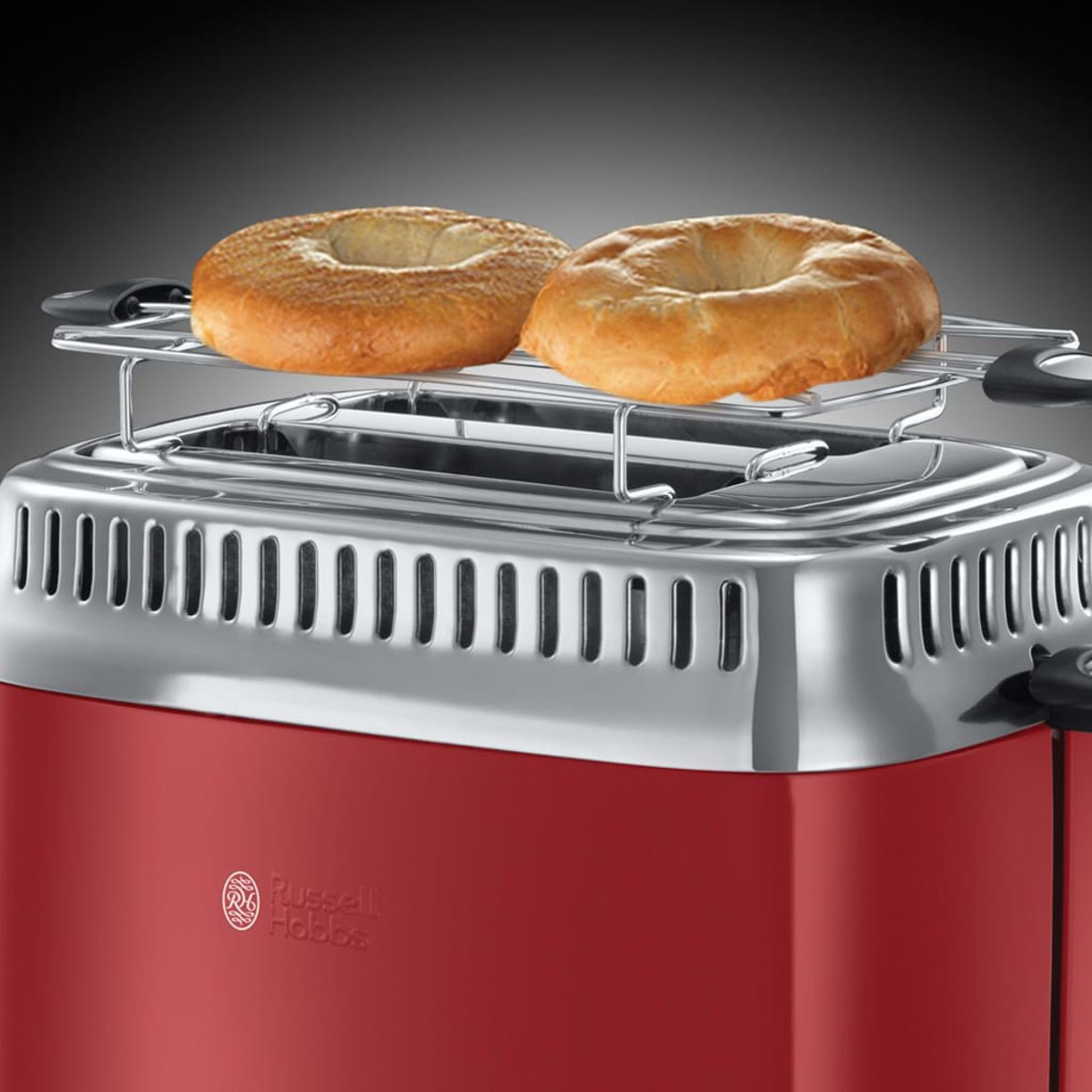 Czerwony toster z dwoma bajglami na górnym ruszcie. Widoczne srebrne akcenty i logo Russell Hobbs.