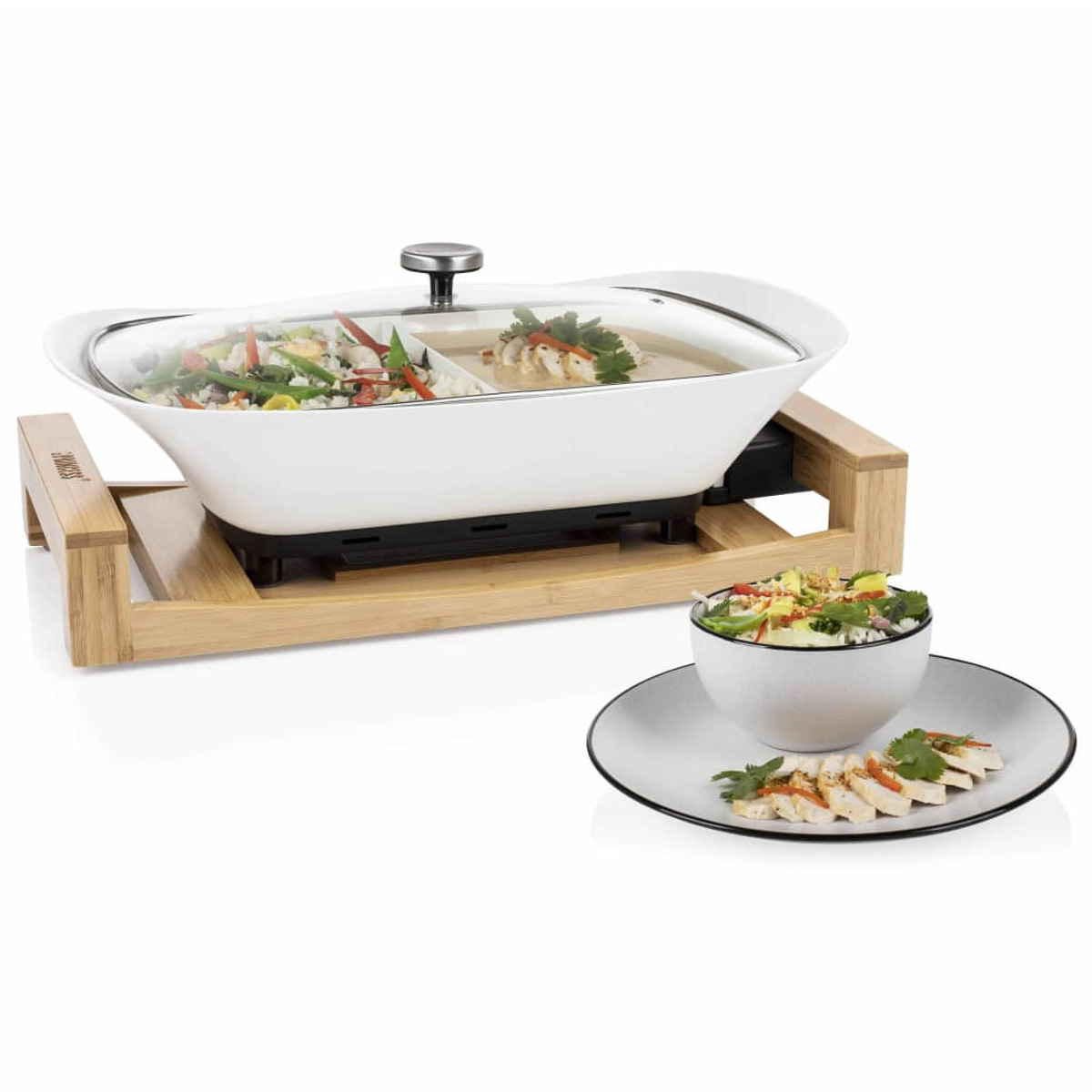 Wok eléctrico blanco con tapa de vidrio, lleno de comida, sobre soporte de madera y guarnición.