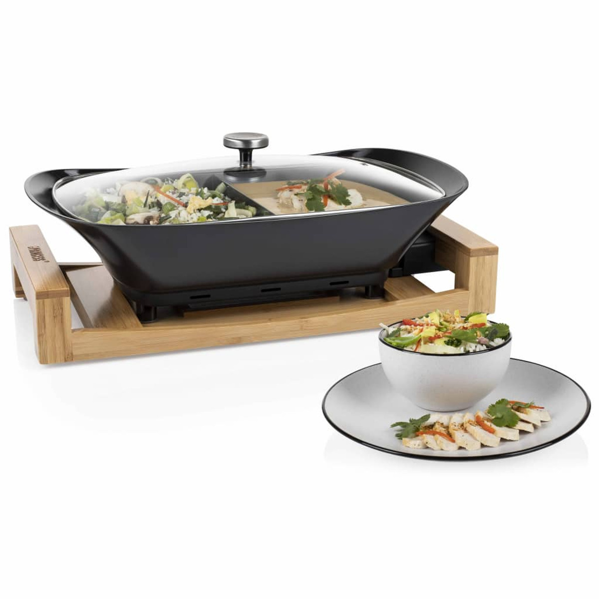 Wok eléctrico con comida. Fondo blanco y un cuenco blanco con comida.