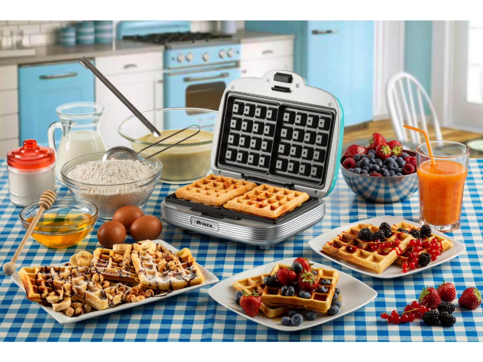 Keuken met wafelijzer, wafels en diverse toppings. Blauw geruit tafelkleed.
