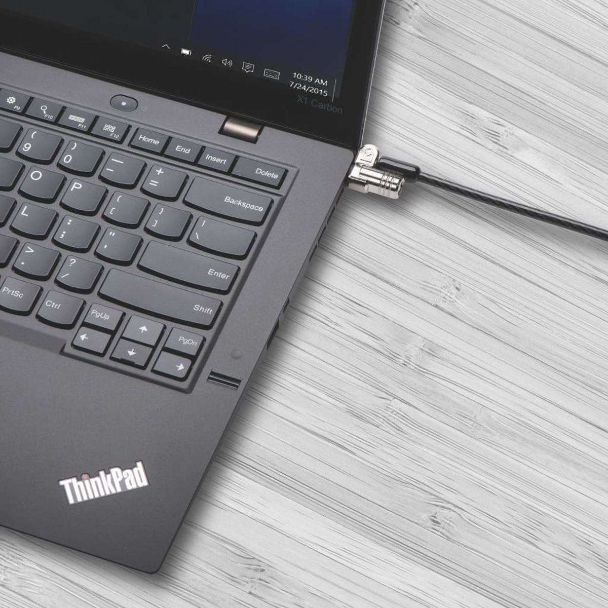 Laptop mit Schloss und Kabel gesichert. Auf einem Holztisch mit Maserung.