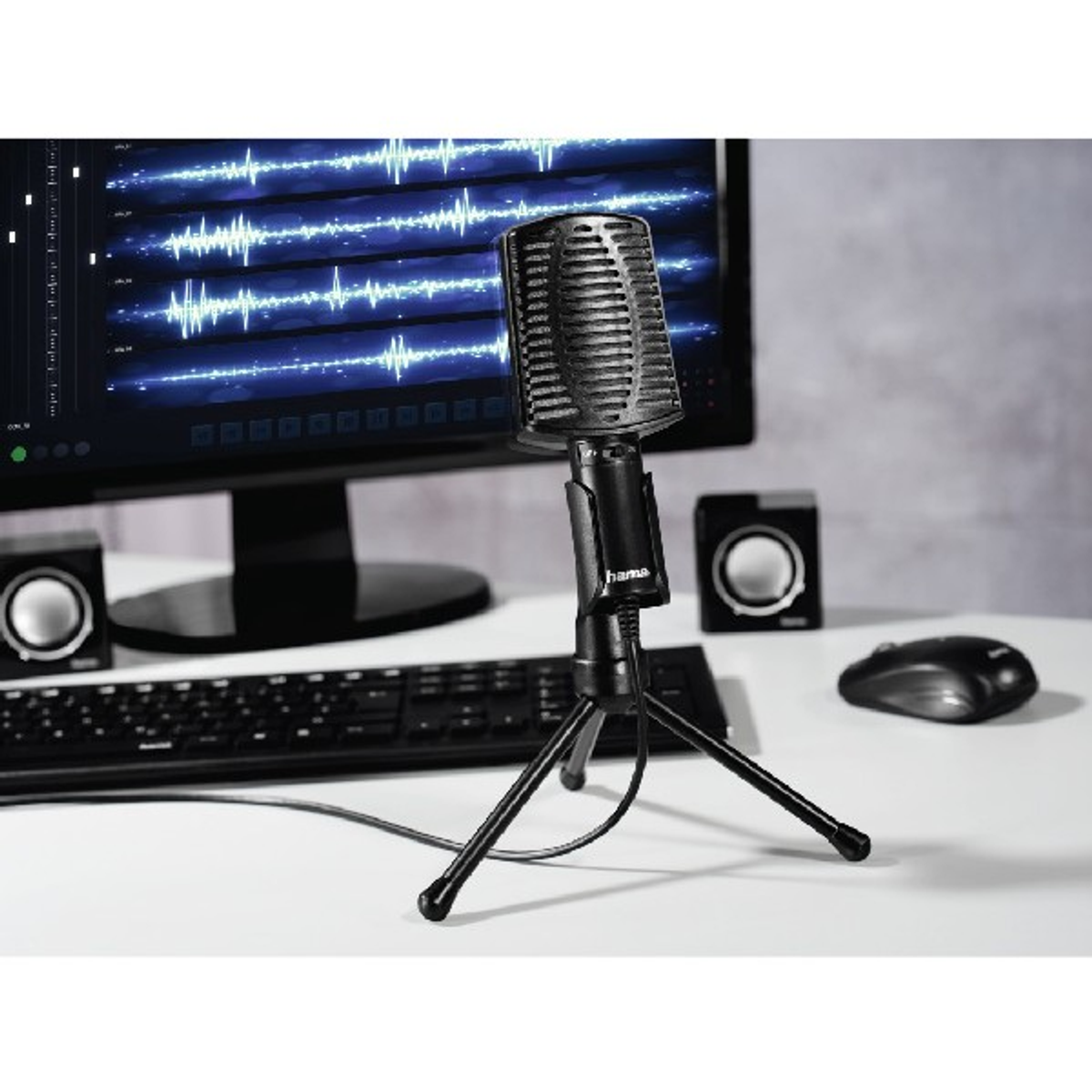 Schwarzes Mikrofon auf einem Stativ. Computerbildschirm mit Audio-Wellenform. Schwarze Lautsprecher und Maus.