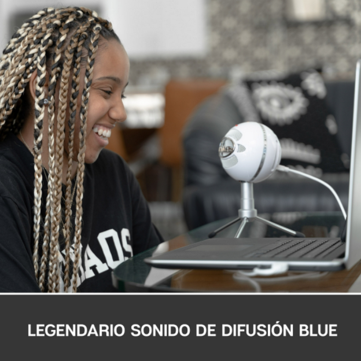 Uśmiechnięta kobieta, w czarnej koszuli, używająca białego mikrofonu z laptopem.