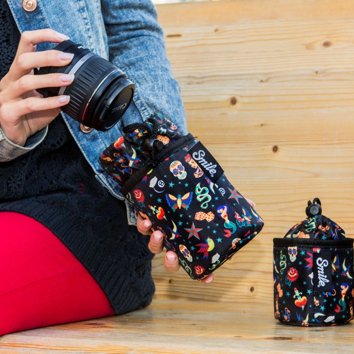 Una persona che tiene una fotocamera e una borsa a fantasia, e una borsa più piccola su una panchina.