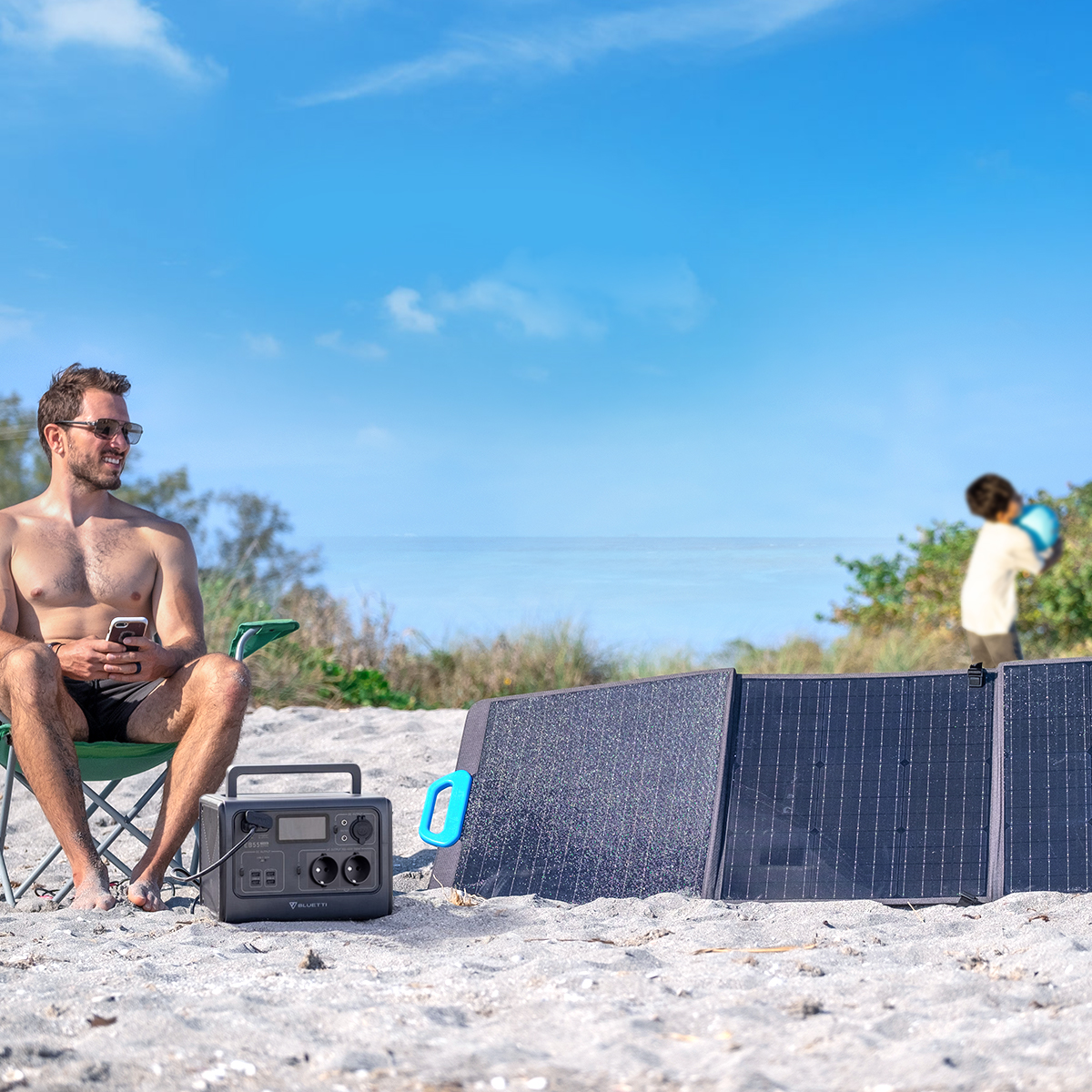 Ein Mann mit Sonnenbrille am Strand in der Nähe eines Kraftwerks und Sonnenkollektoren.
