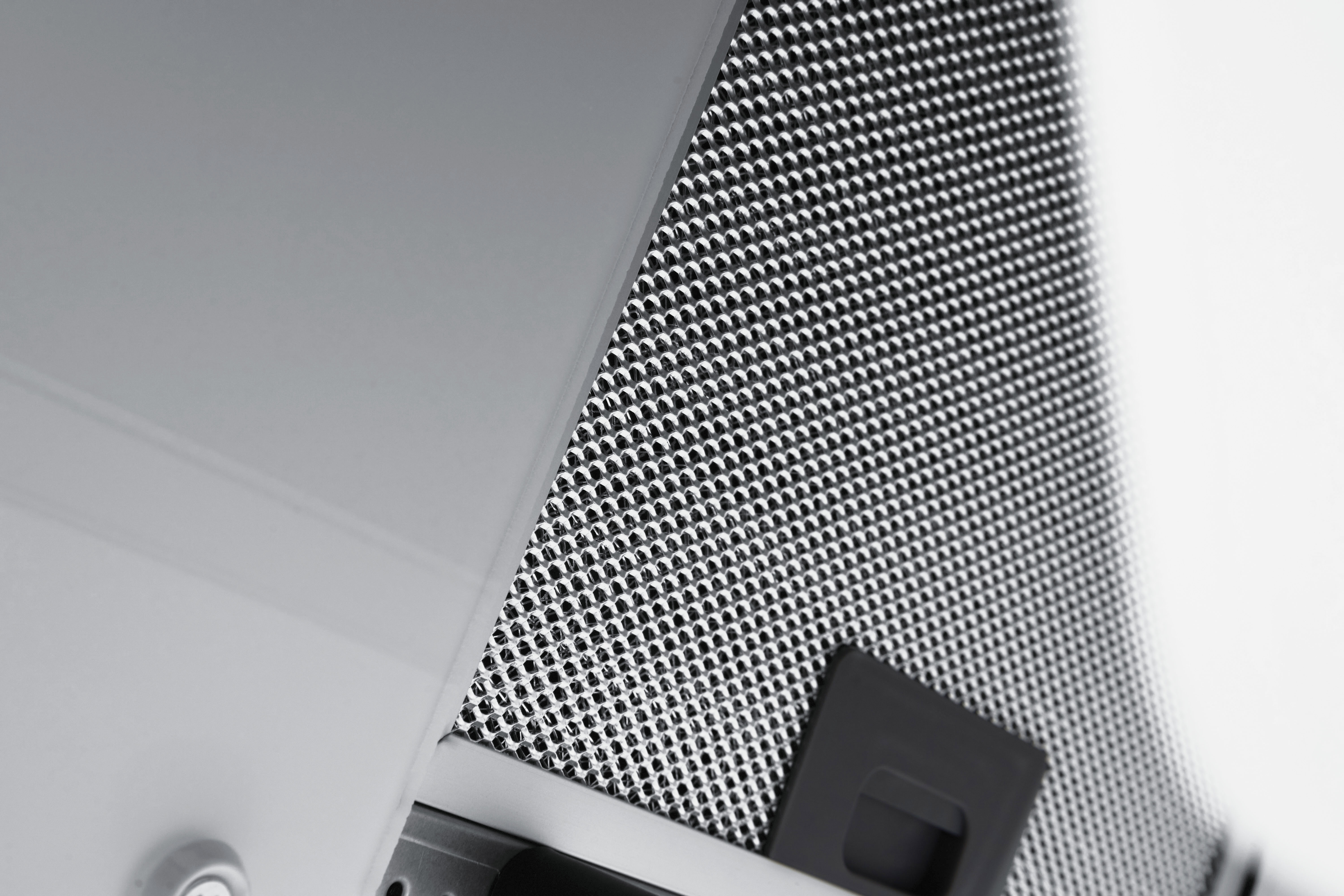 Close-up of a metallic, perforated surface with a rectangular, black control panel.
