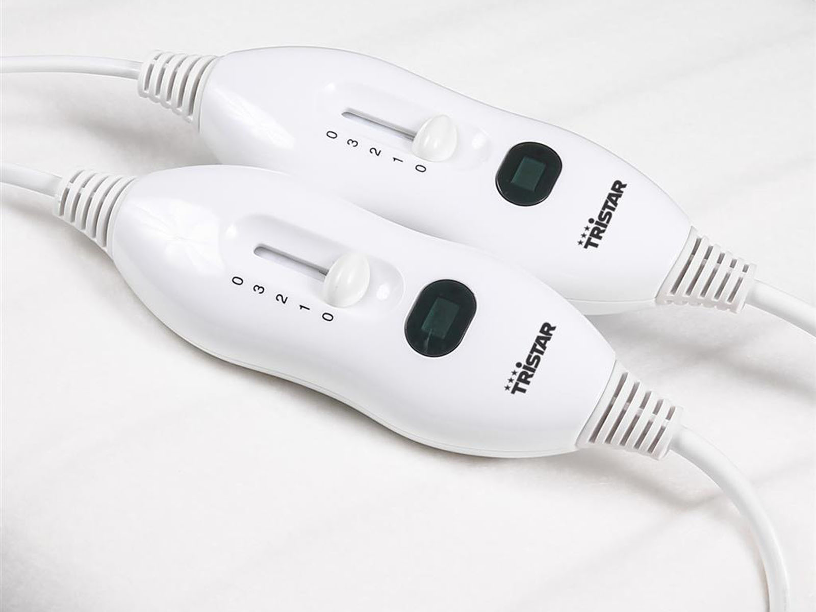 Dwa białe kontrolery do koca elektrycznego Tristar z pokrętłami, ustawieniami 0-3 i zielonym światłem.