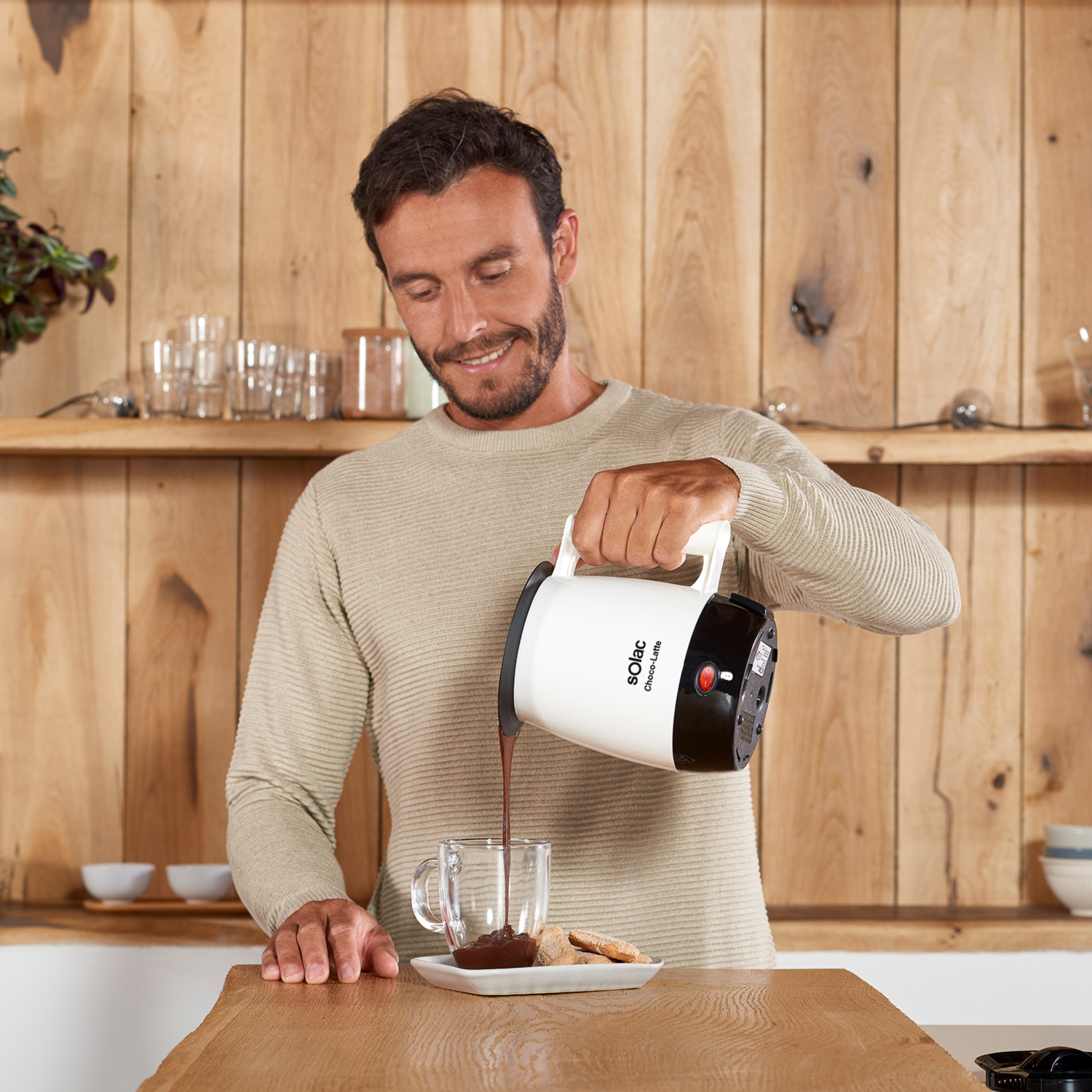 Un hombre vertiendo chocolate caliente en un vaso desde una chocolatera Solac.