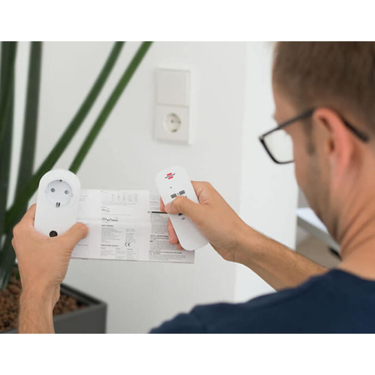 Mann hält Fernbedienung und Stecker, mit Steckdose und Fernbedienungsempfänger.