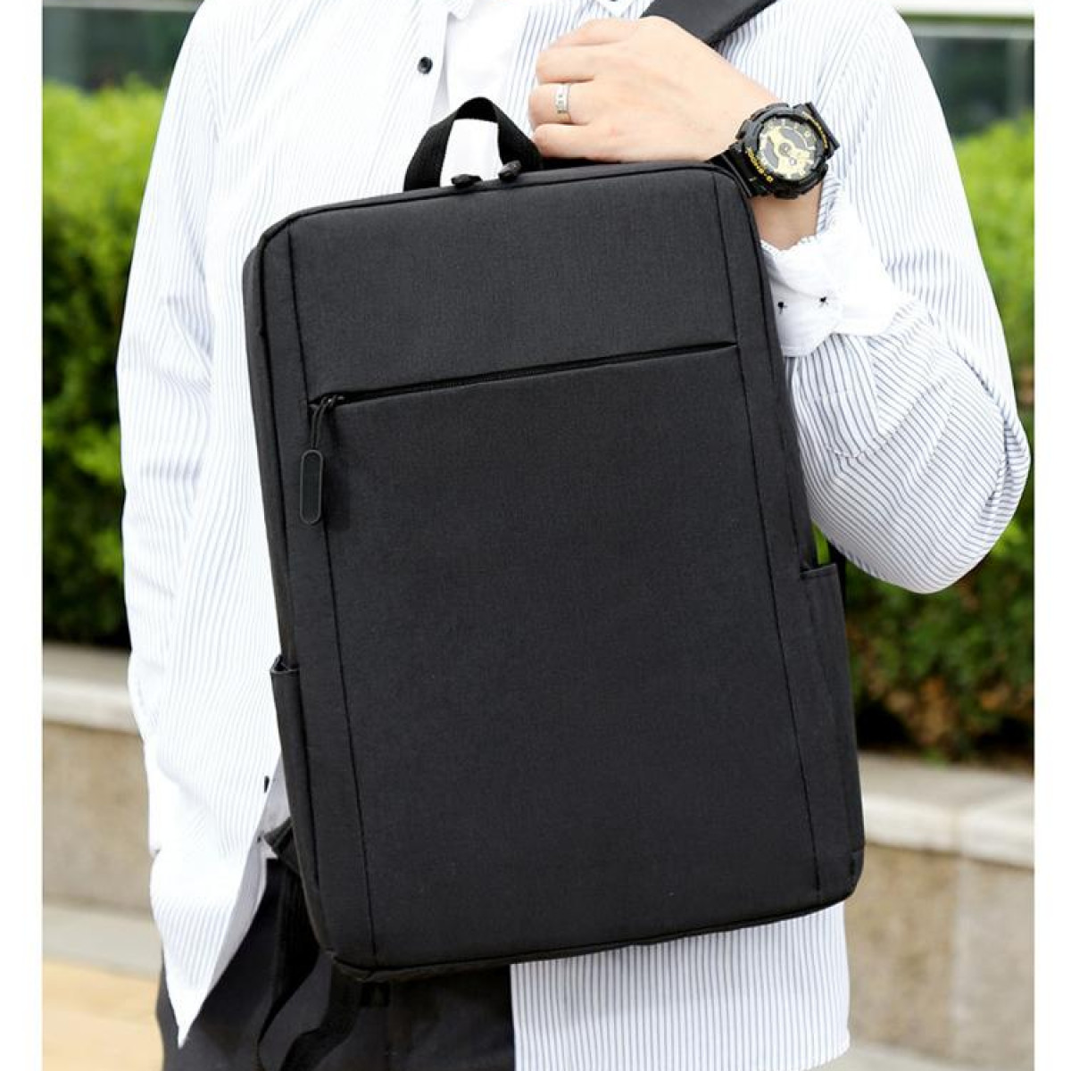 Mężczyzna z czarnym plecakiem, w białej koszuli i zegarkiem.