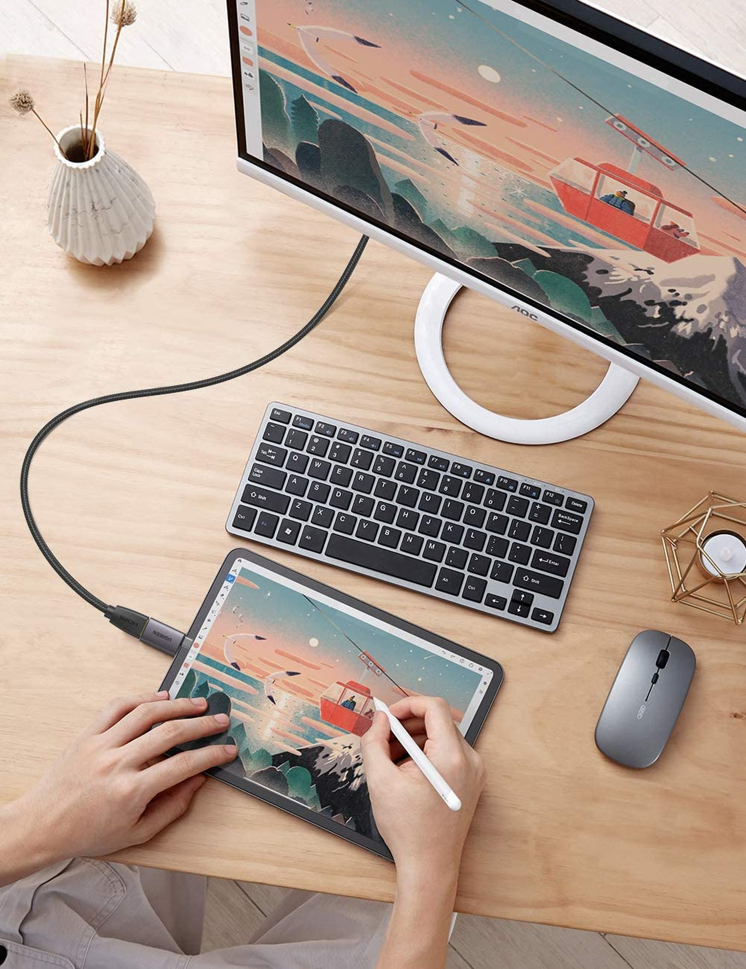 Eine Person, die einen Stift auf einem Tablet verwendet, das mit Monitor, Tastatur und Maus verbunden ist.