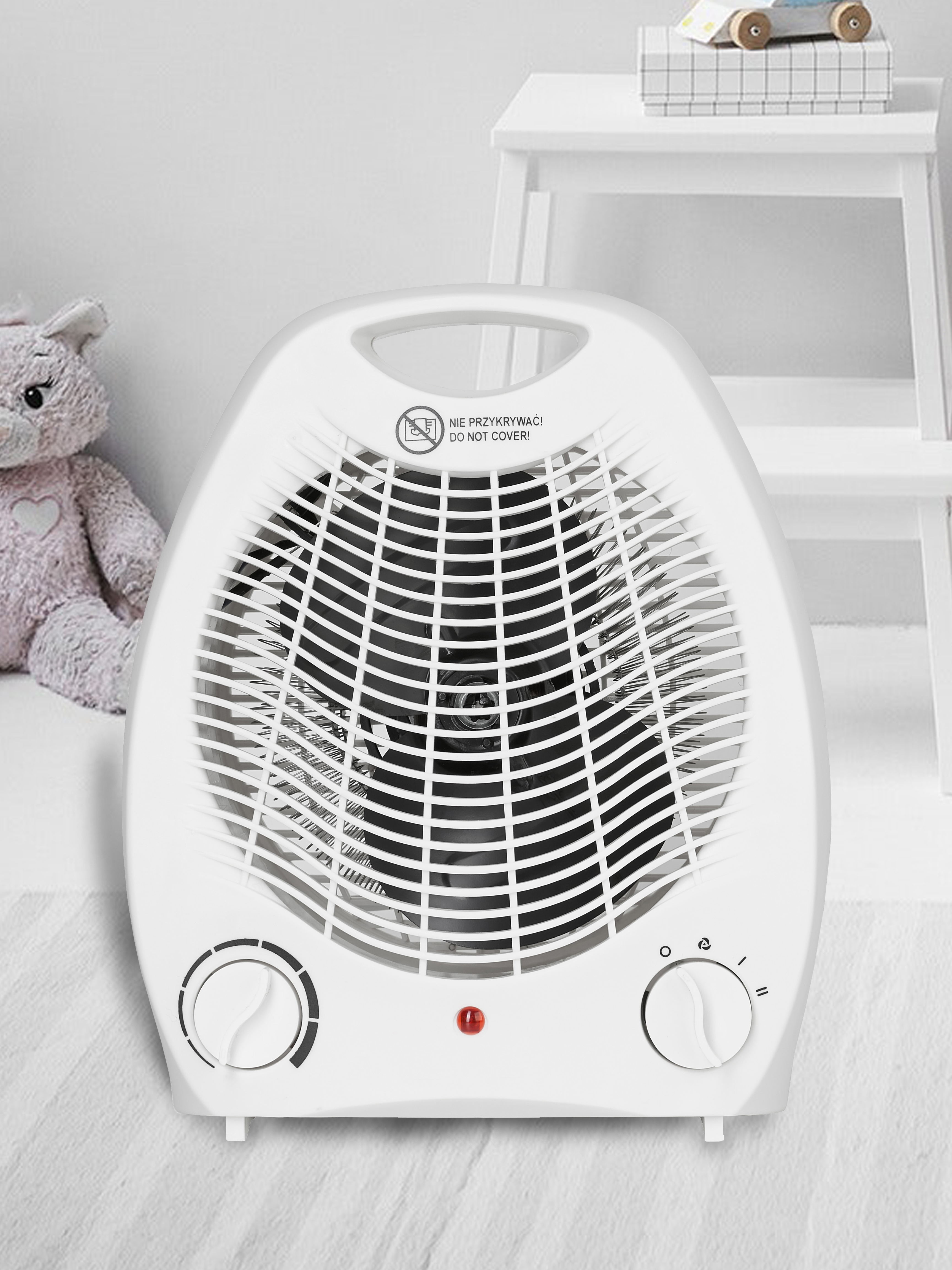 Calentador eléctrico blanco en un suelo blanco. Un oso de peluche y una mesita en el fondo.