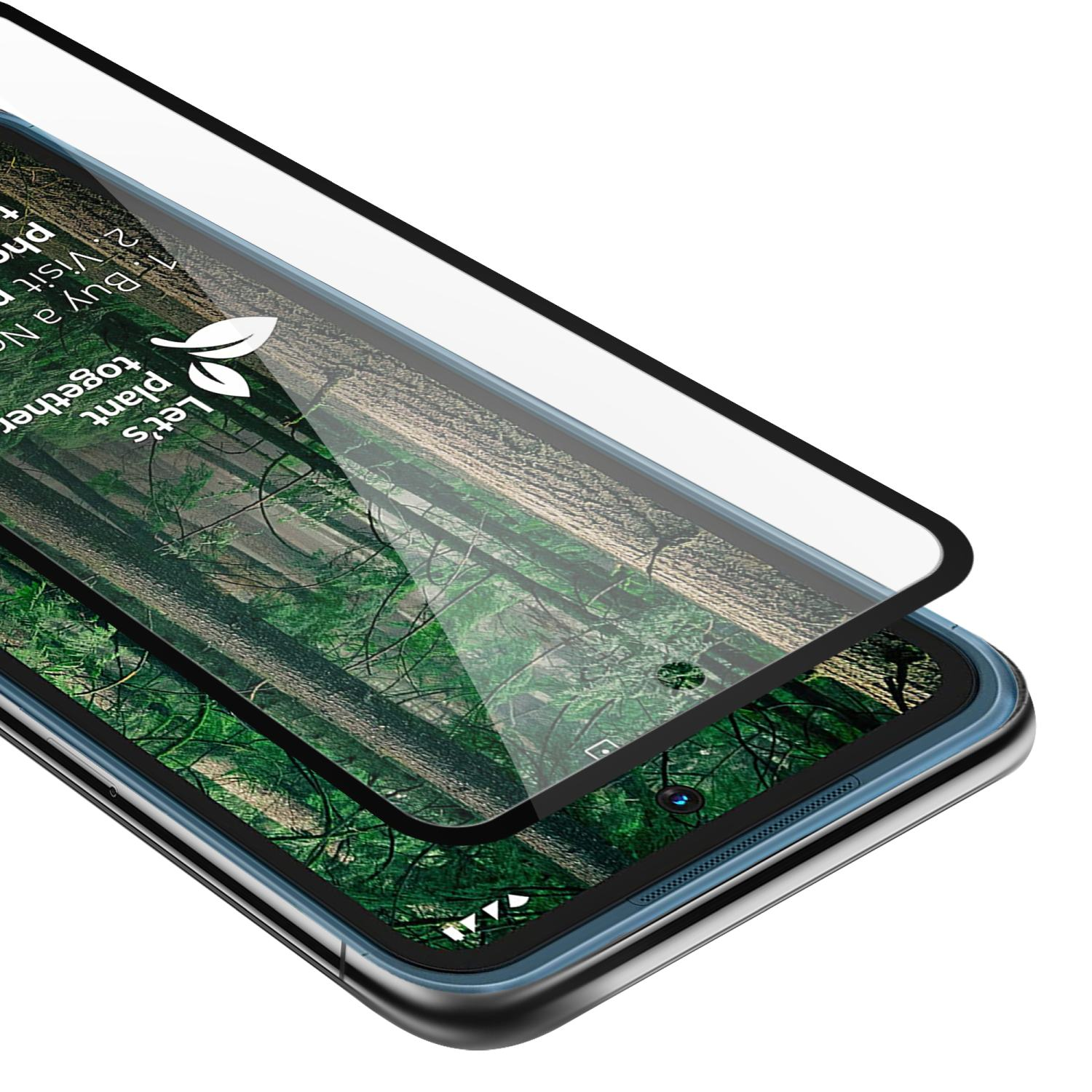 Un telefono con una protezione per lo schermo in fase di applicazione. Il telefono ha una scena di foresta come sfondo.