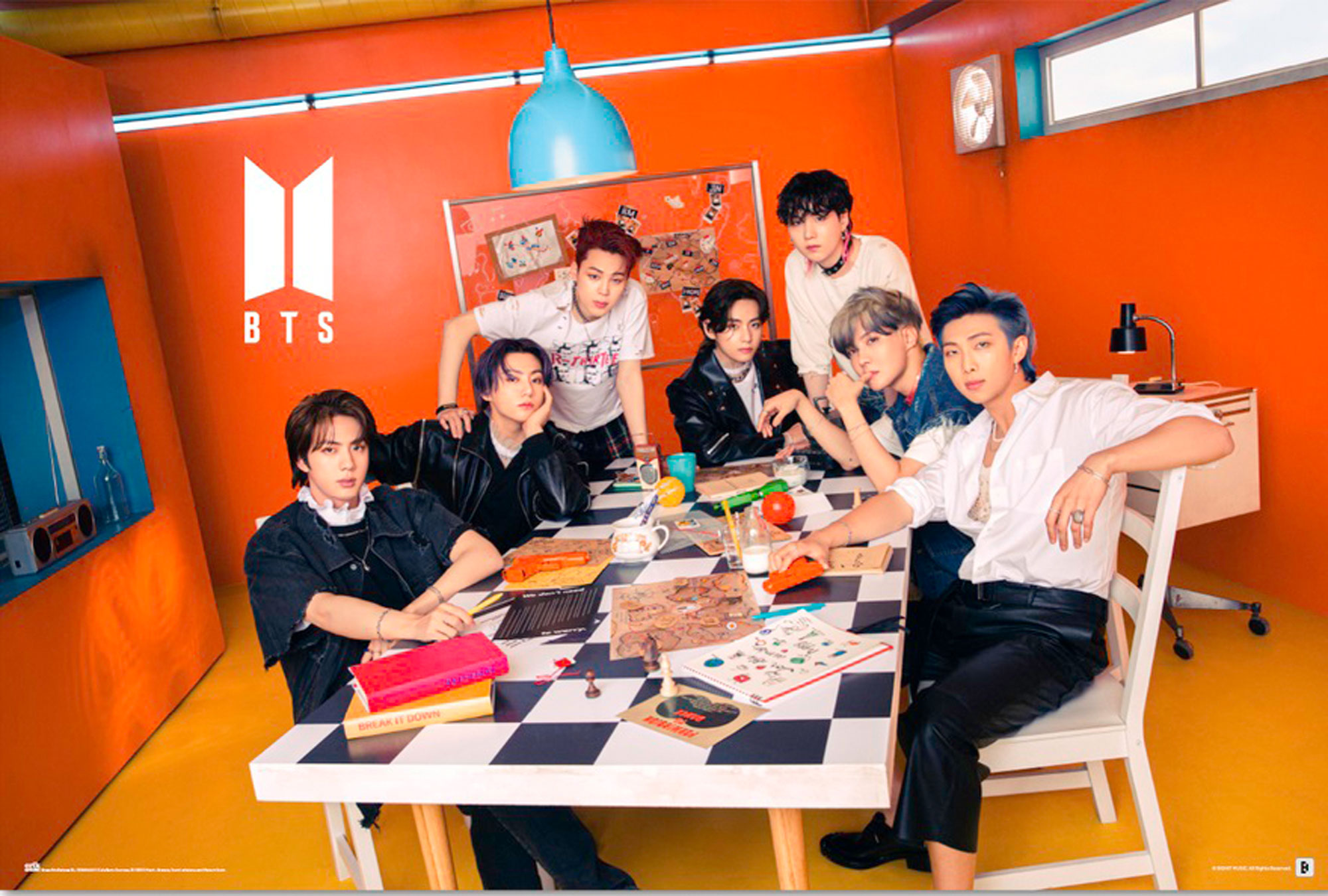 BTS-Gruppenfoto. Sieben Männer sitzen in einem orangefarbenen Raum an einem Tisch.