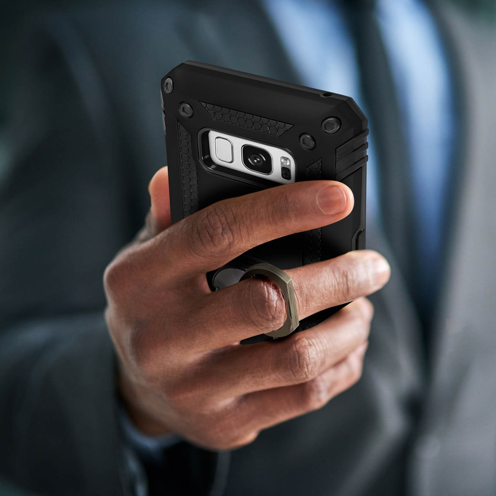 Una mano che tiene una custodia nera per telefono con anello.