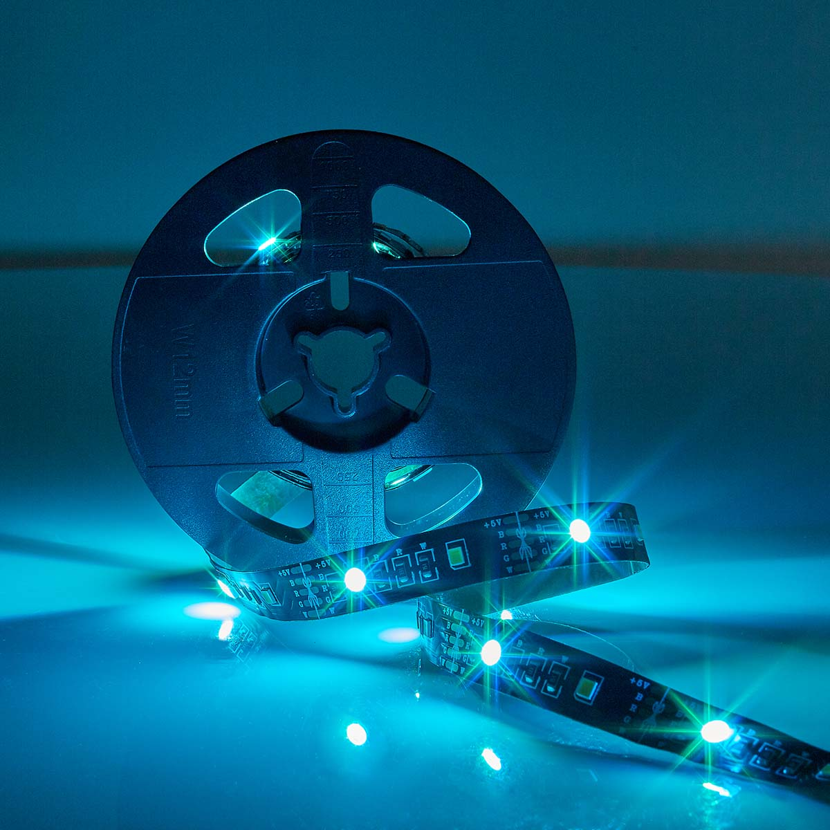 Een rol blauwe LED-strips met verlichte lampjes, op een blauw oppervlak.
