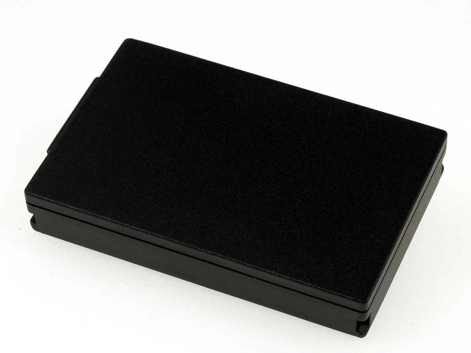 Un objeto rectangular negro con una superficie texturizada, probablemente una batería o un componente de dispositivo.
