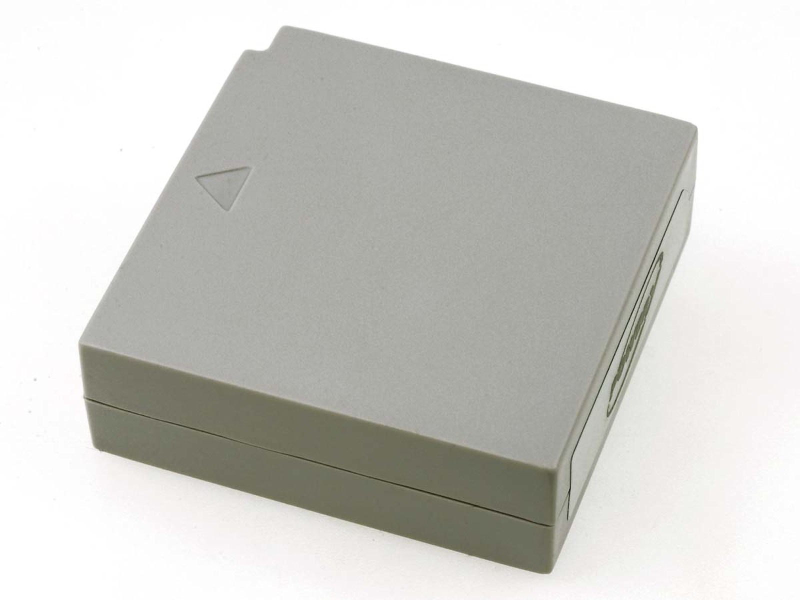 Carcasa de batería gris con una marca triangular en la superficie superior, fondo blanco.