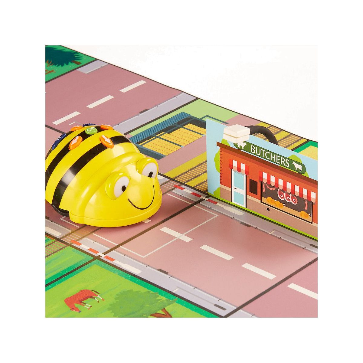 Una abeja de juguete en una carretera con una carnicería de juguete. La abeja es amarilla con rayas negras.