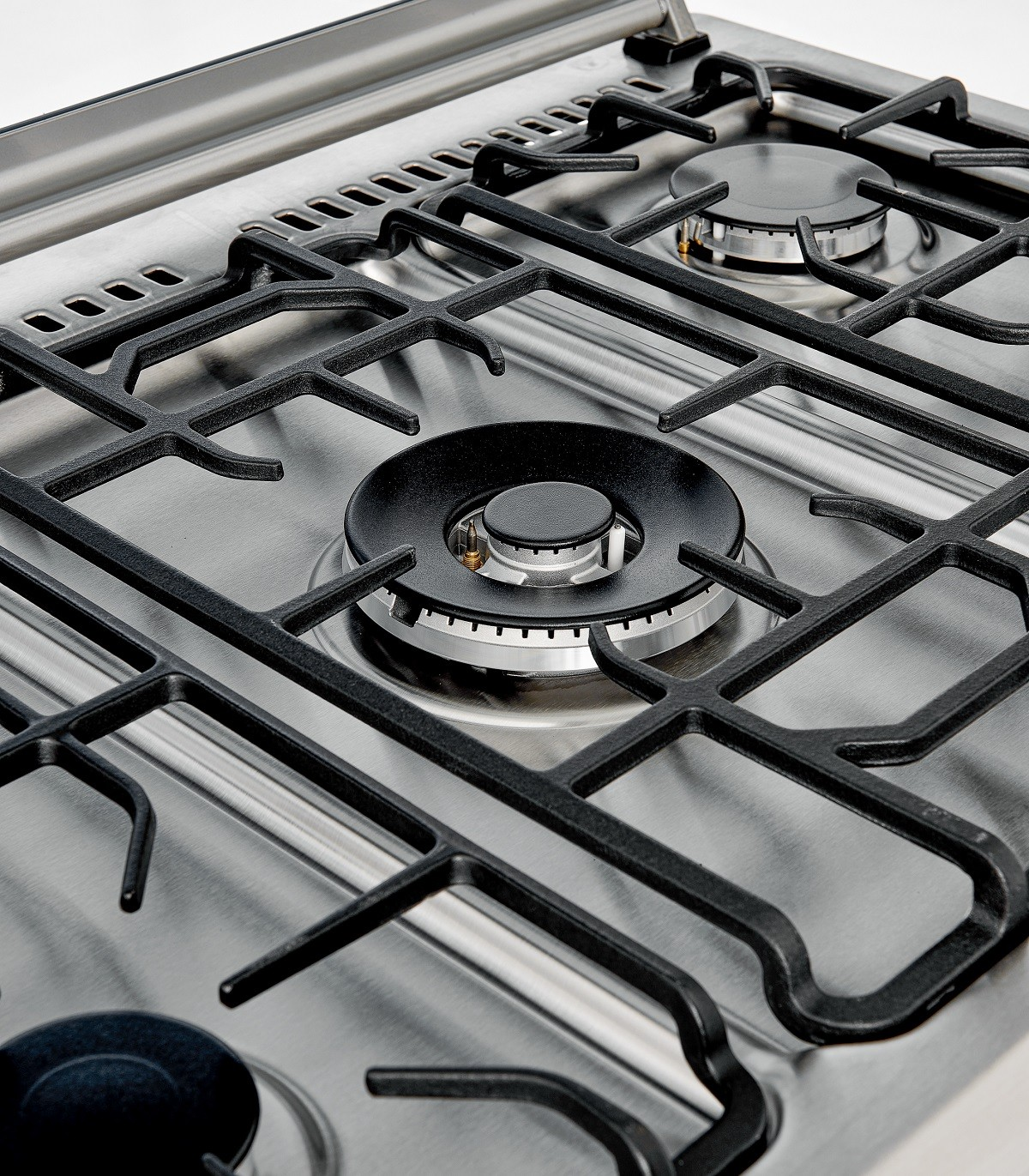 Primer plano de una estufa de gas de acero inoxidable con parrillas y quemadores negros, mostrando una superficie metálica.