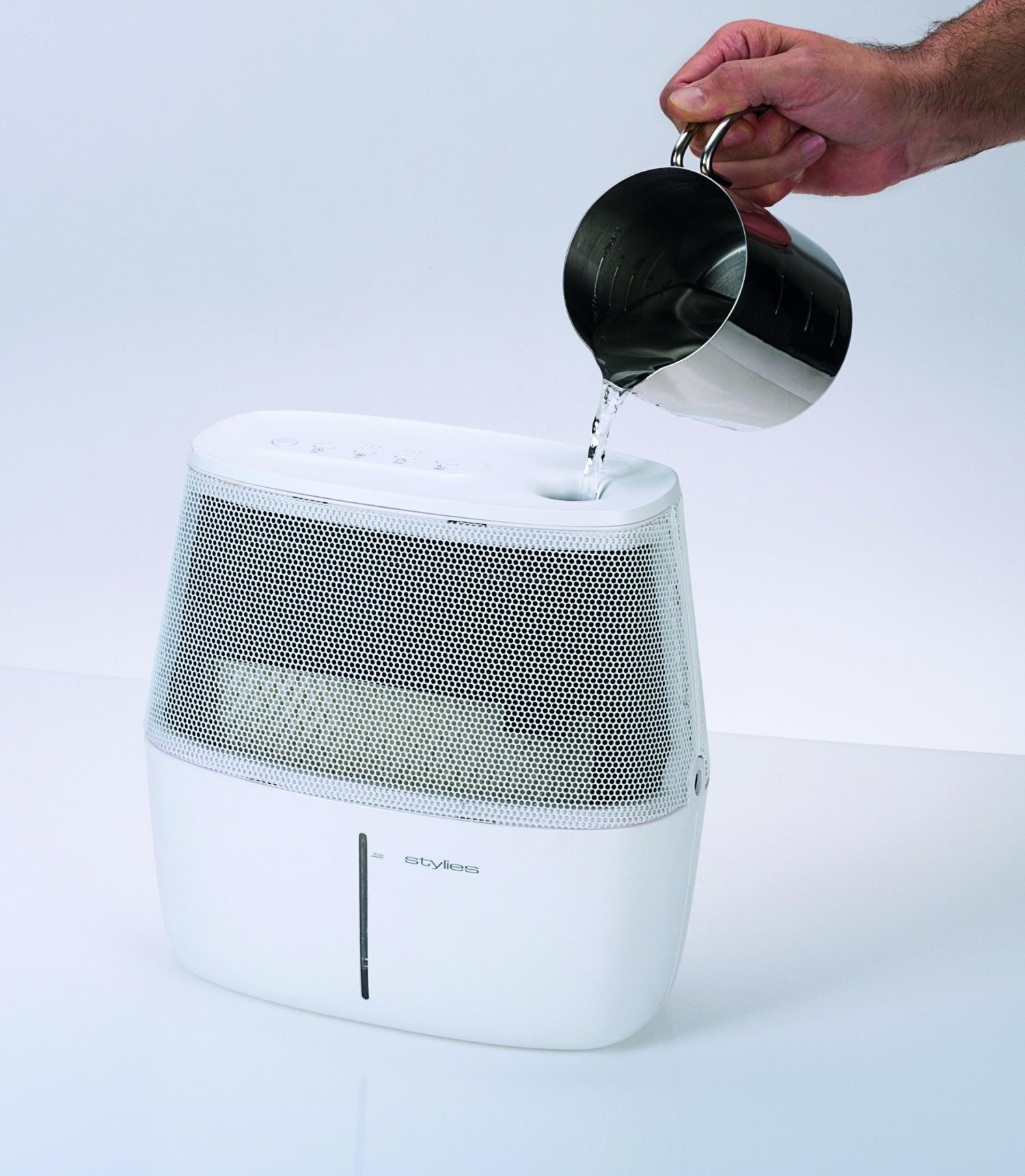 Agua vertiéndose en un humidificador blanco. El humidificador tiene una parte superior cubierta de malla.