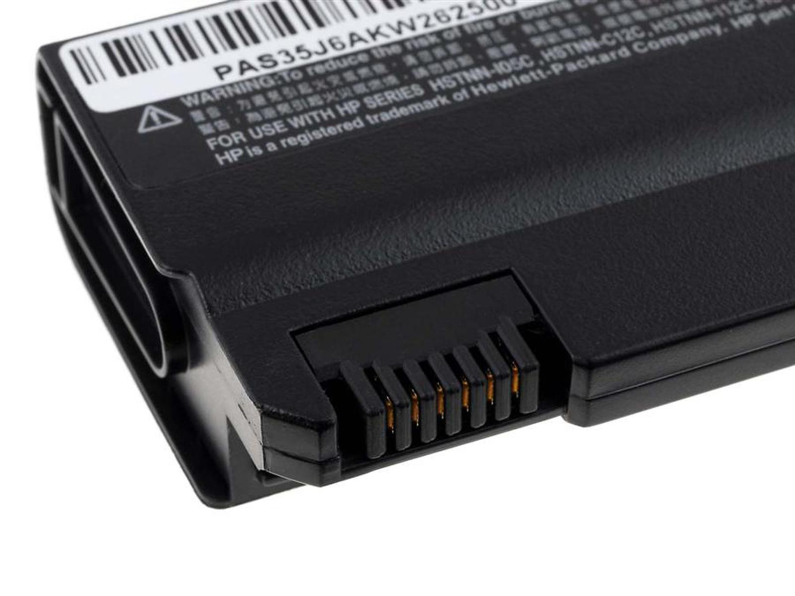 Primer plano de un conector de batería de portátil con una etiqueta de advertencia.