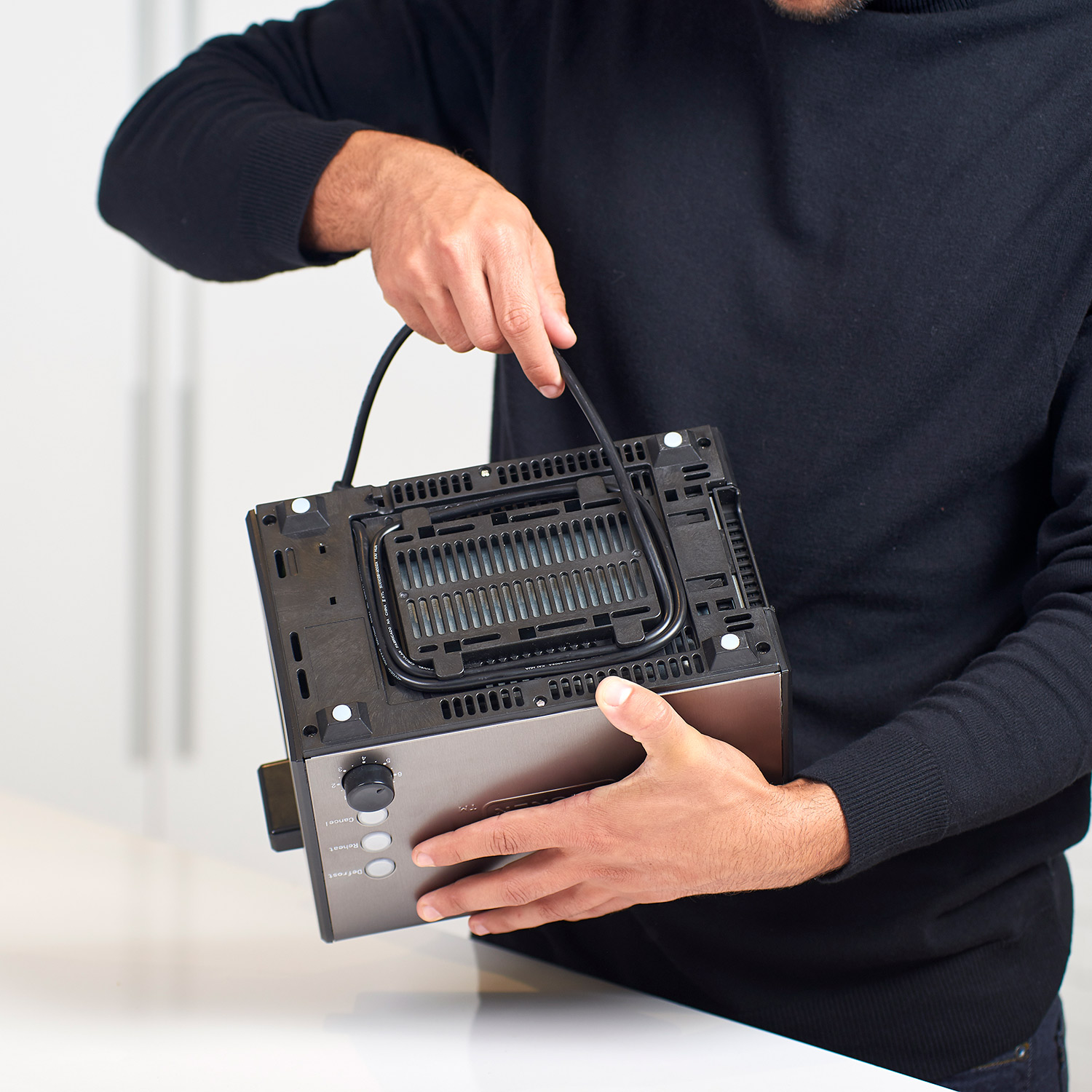 Osoba trzymająca spód tostera, pokazująca przewód i elementy.