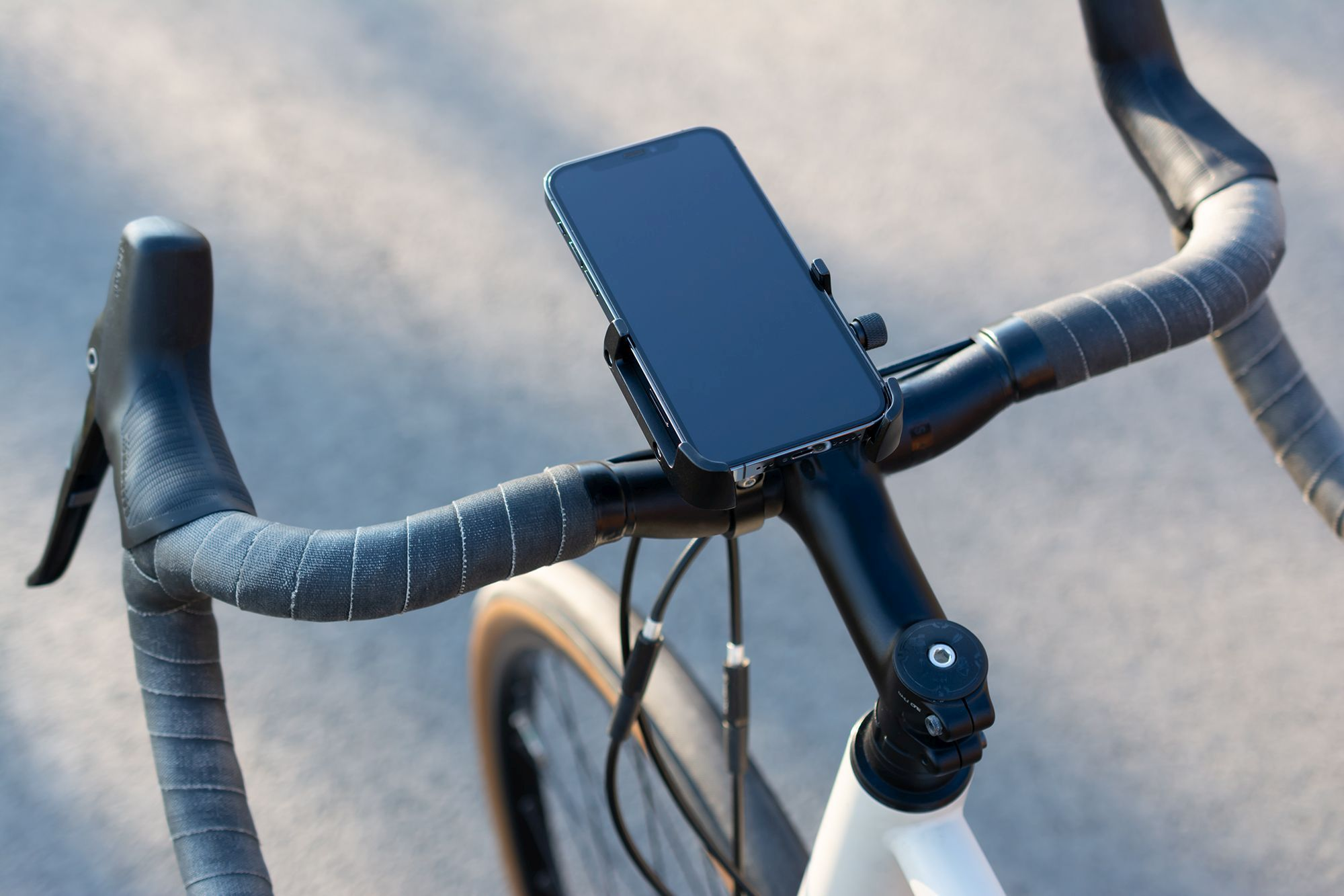 Smartphone an einem Fahrradlenker befestigt. Das Telefon ist schwarz, der Lenker schwarz und grau.