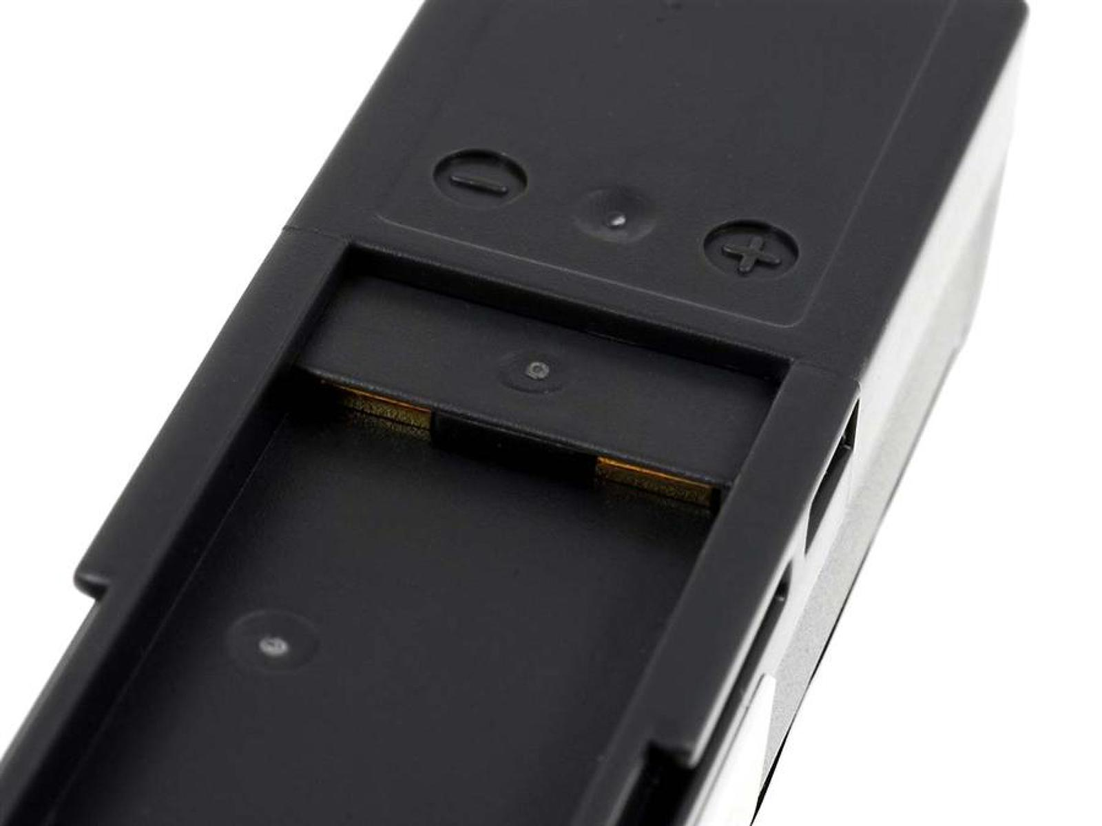 Primer plano de un compartimento de batería negro con marcas positivas y negativas y contactos metálicos en el interior.