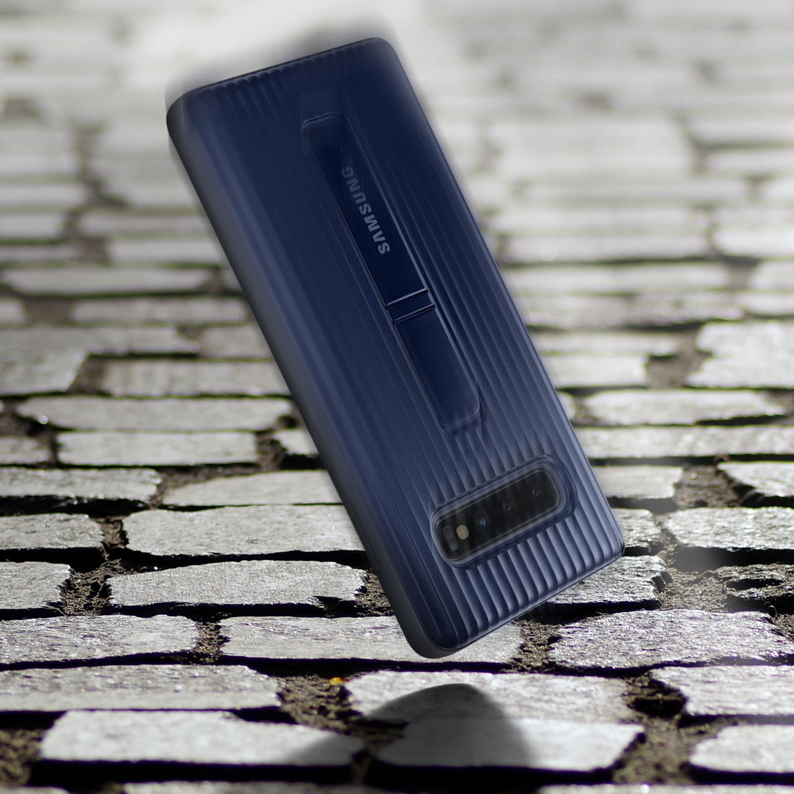 Een blauwe telefoonhoes met een standaard valt op een stenen oppervlak. De hoes heeft een Samsung logo.