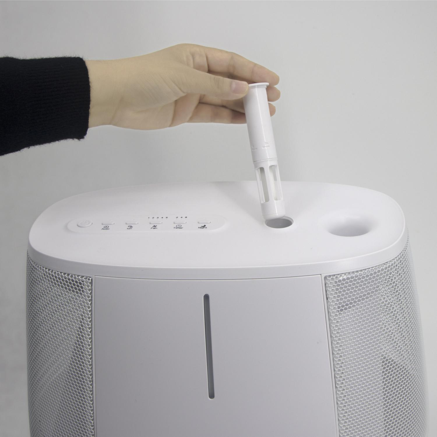 Una mano inserisce un filtro bianco in un umidificatore bianco. Sfondo bianco.
