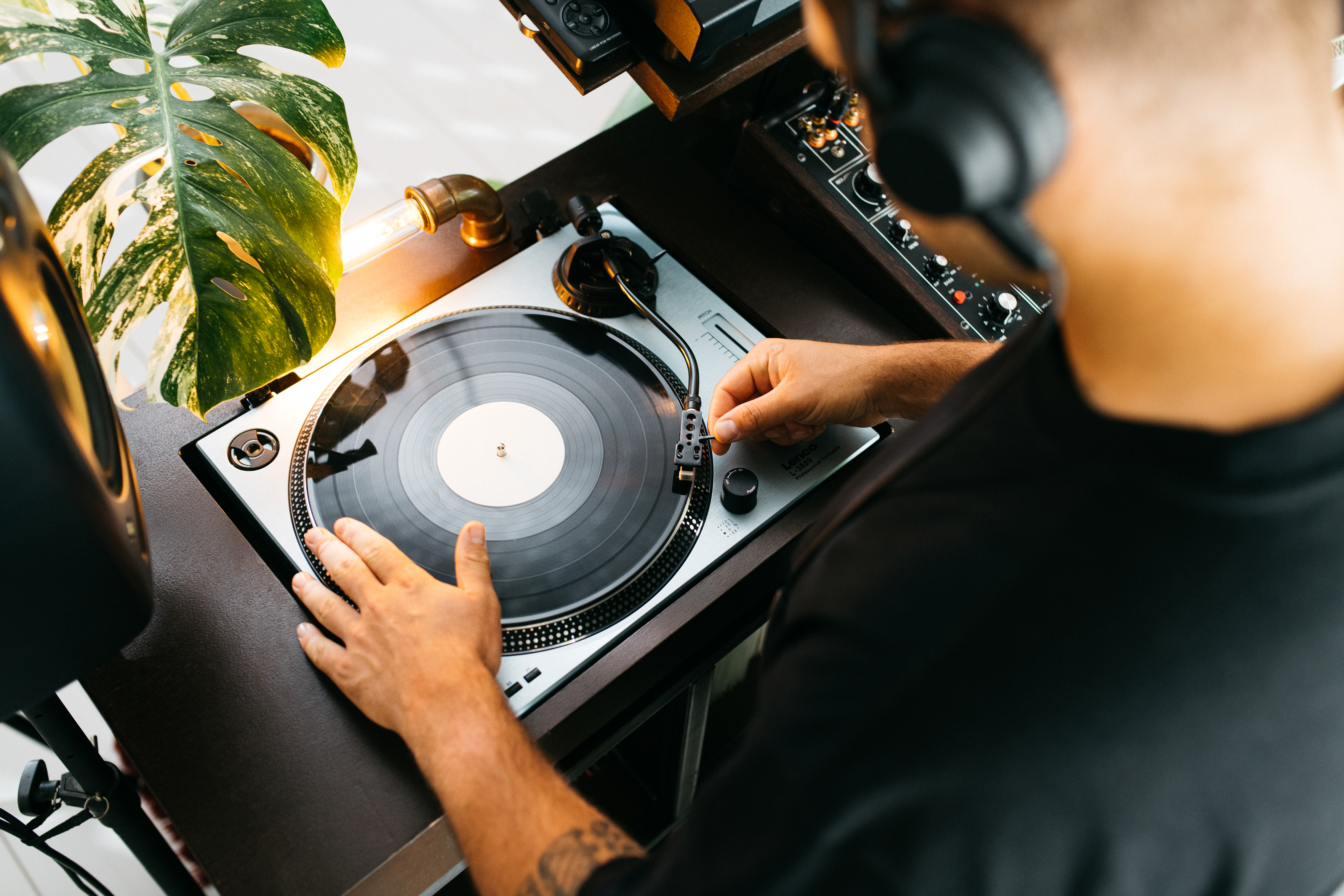 DJ używający gramofonu z płytą winylową. Ma na sobie słuchawki.