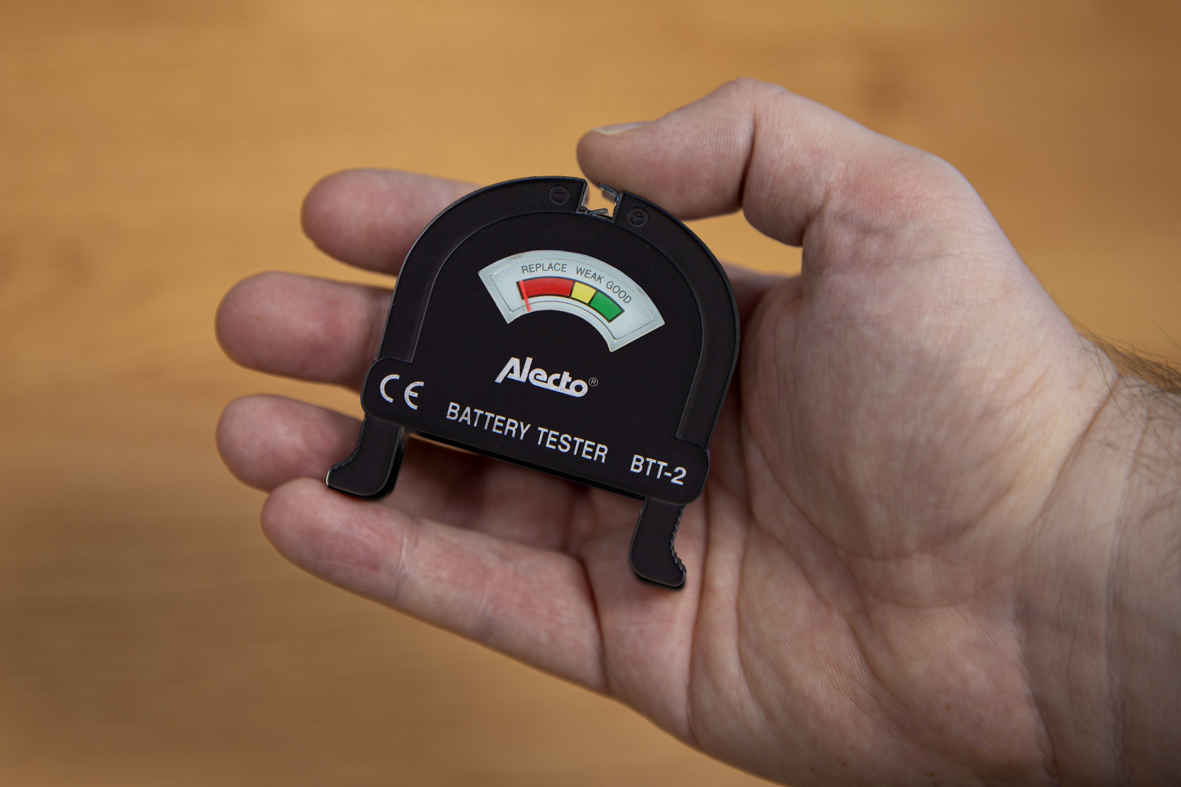 Hand hält Batterietester, mit Gut-Schwach-Anzeigen.