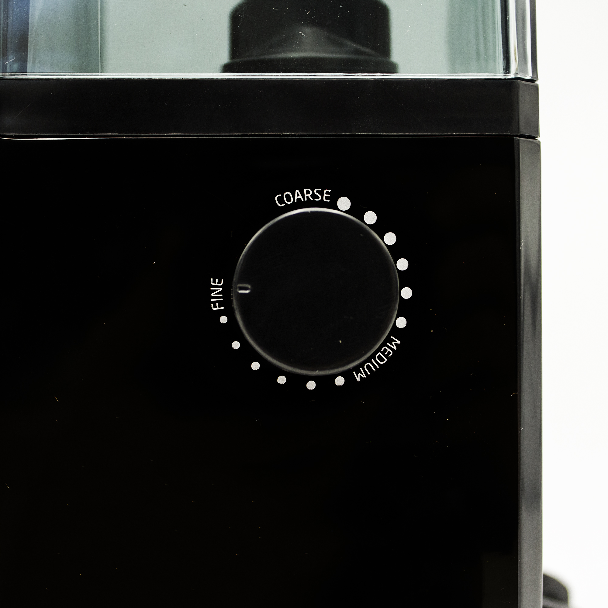 Primer plano de un molinillo de café negro con un dial etiquetado 'FINO', 'MEDIO' y 'GRUESO'.