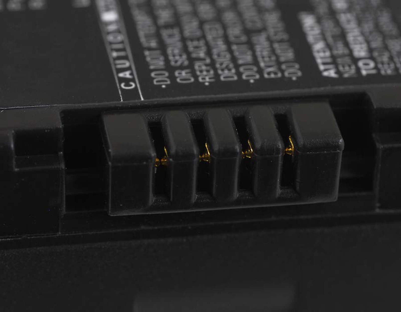 Conector de batería negro con pines dorados. El conector tiene forma rectangular.