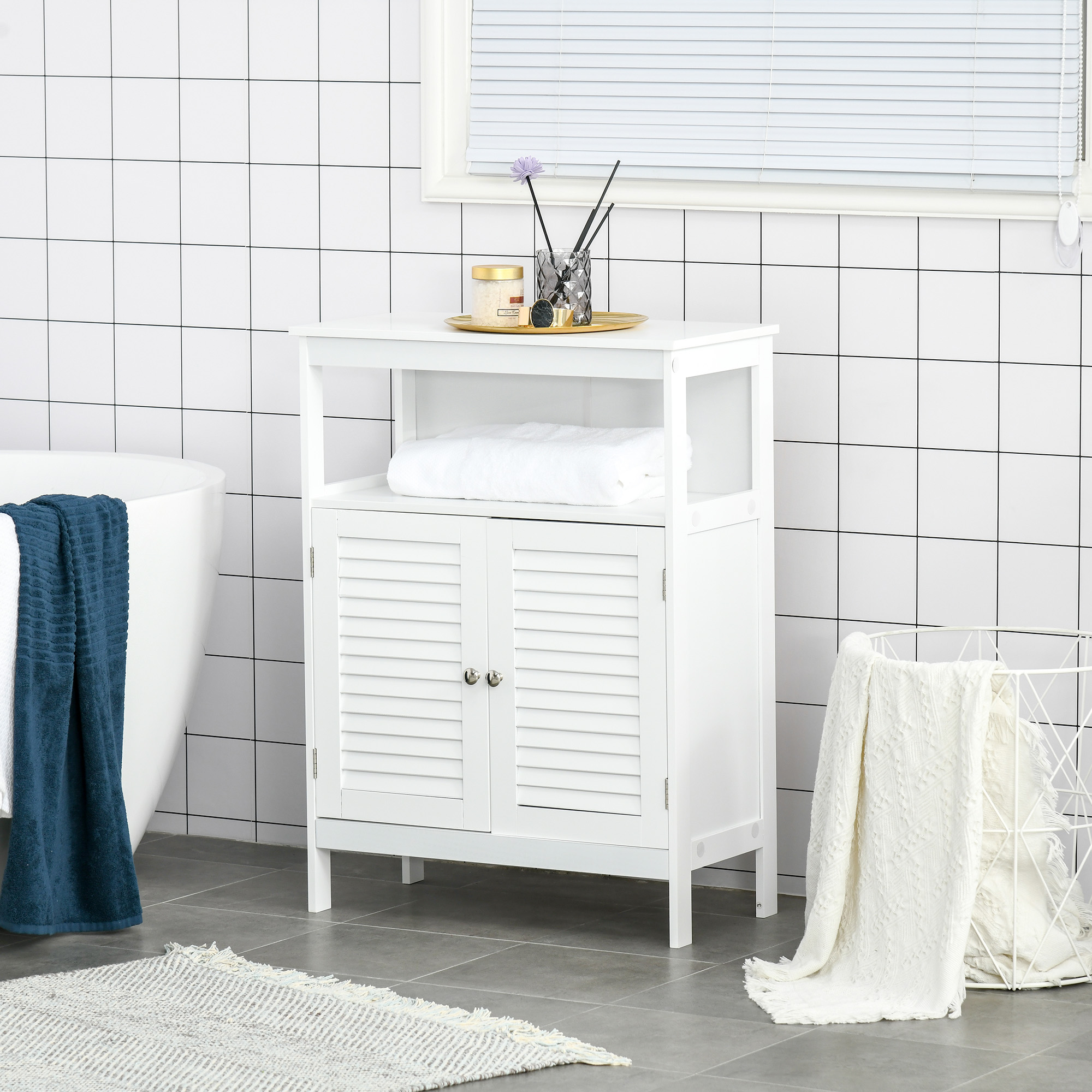 Un armario de baño blanco con puertas de lamas junto a una bañera con toallas oscuras.